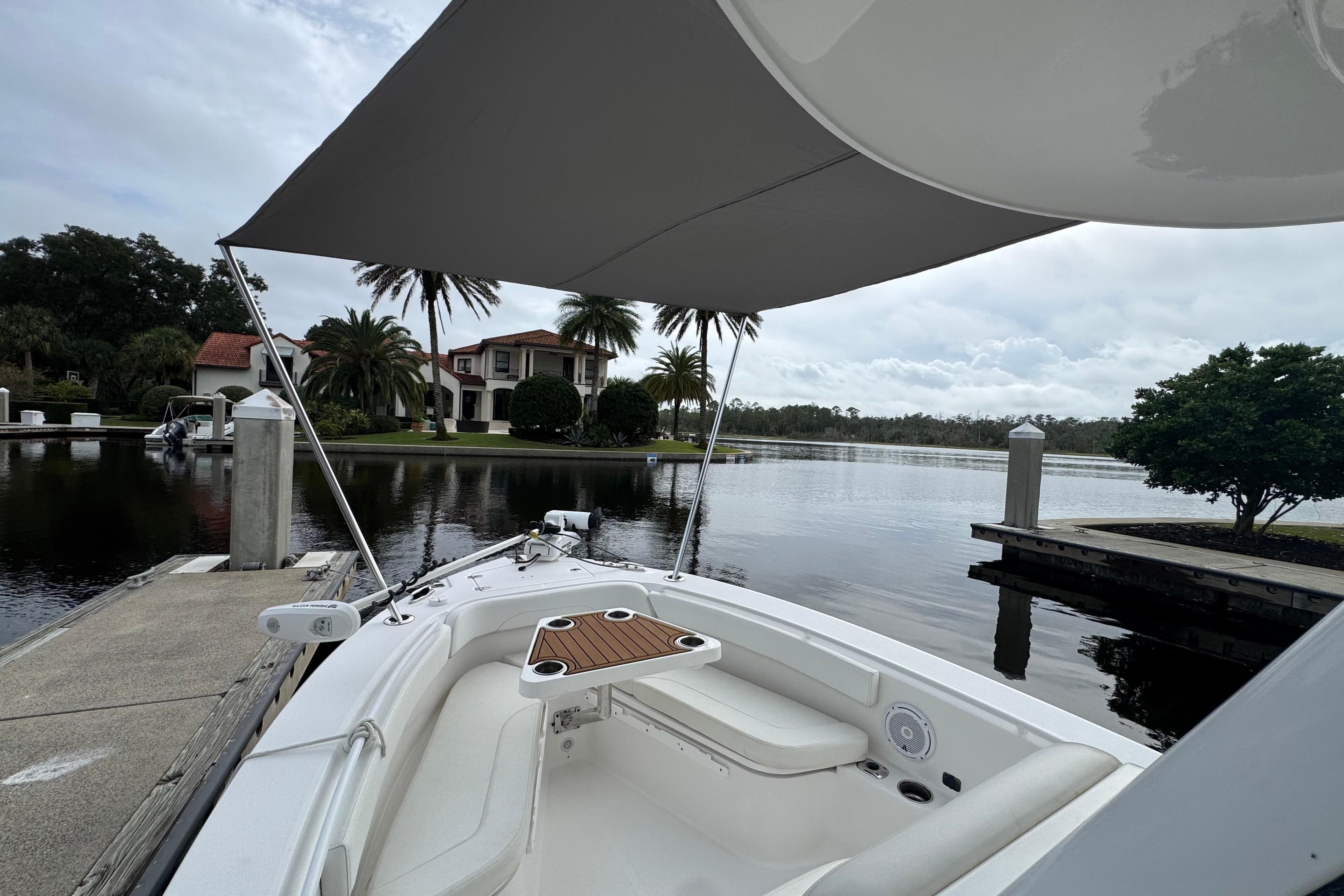 2019 Edgewater 230CC boat docked by a serene waterfront with lush greenery.