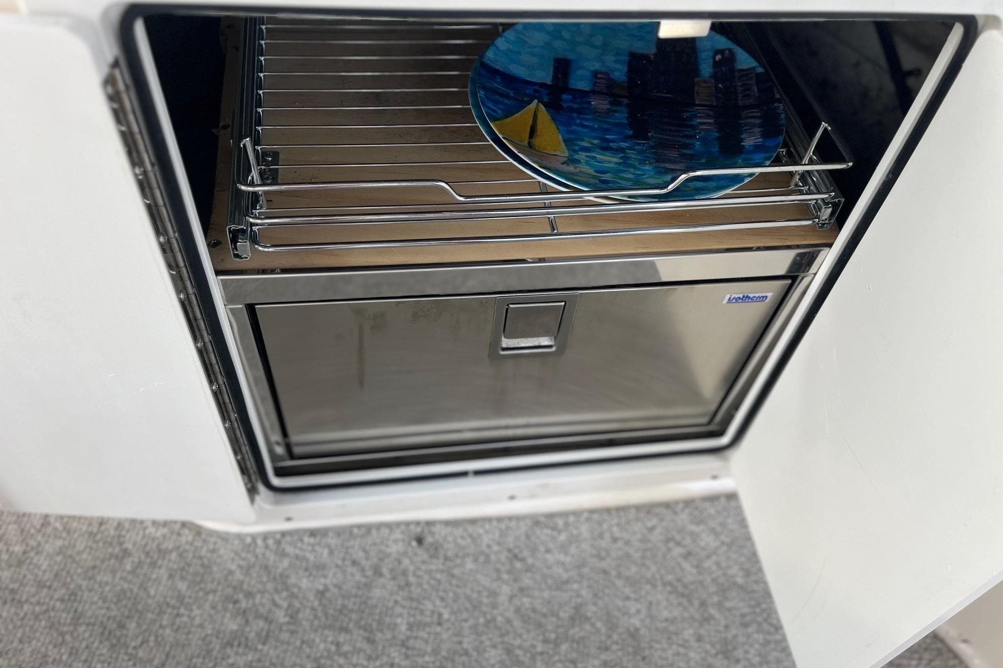 2004 Rinker Fiesta Vee 270 boat interior with a stainless steel drawer and colorful plate.