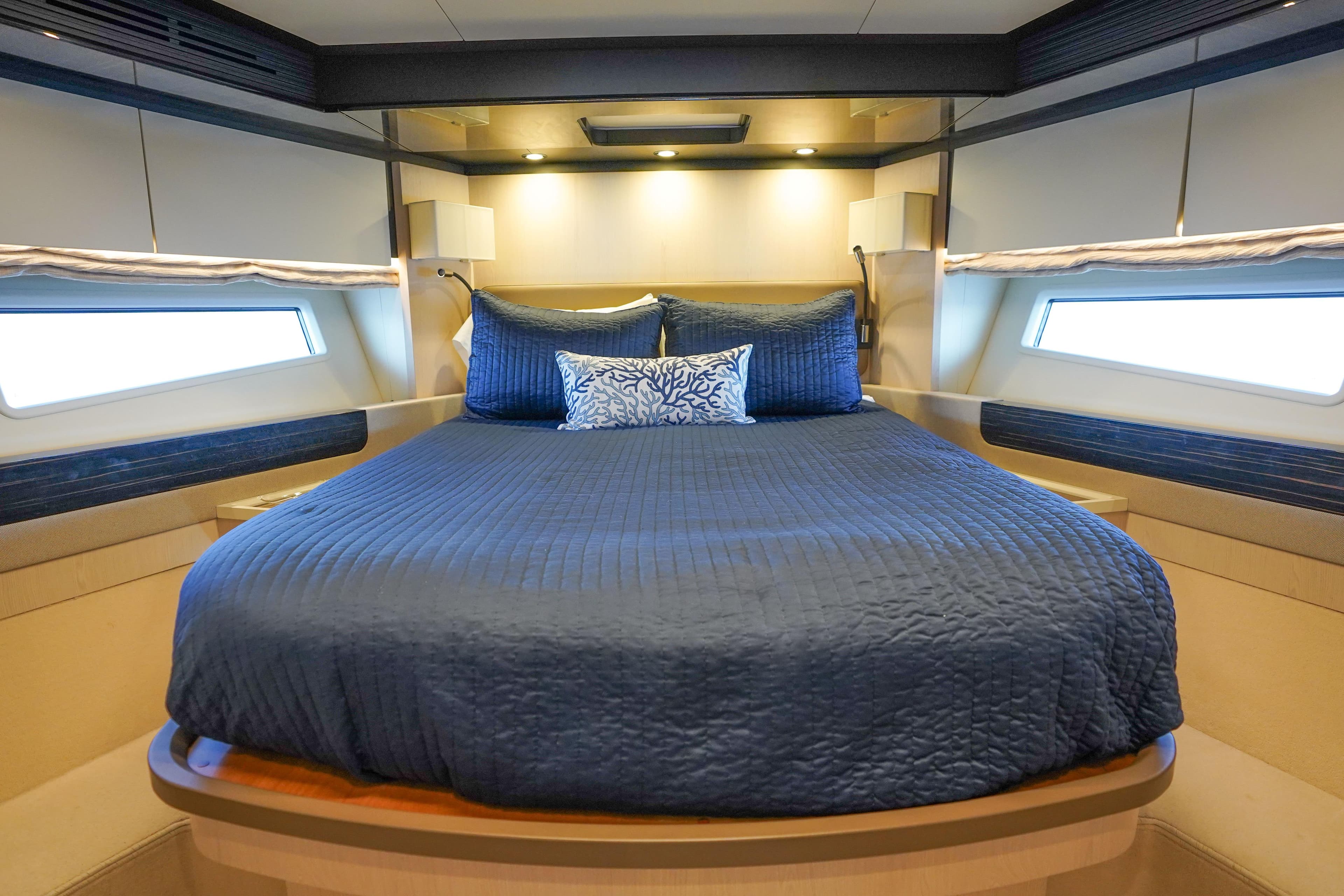 Luxurious bedroom interior of 2017 Azimut 66 Flybridge yacht with blue bedding.