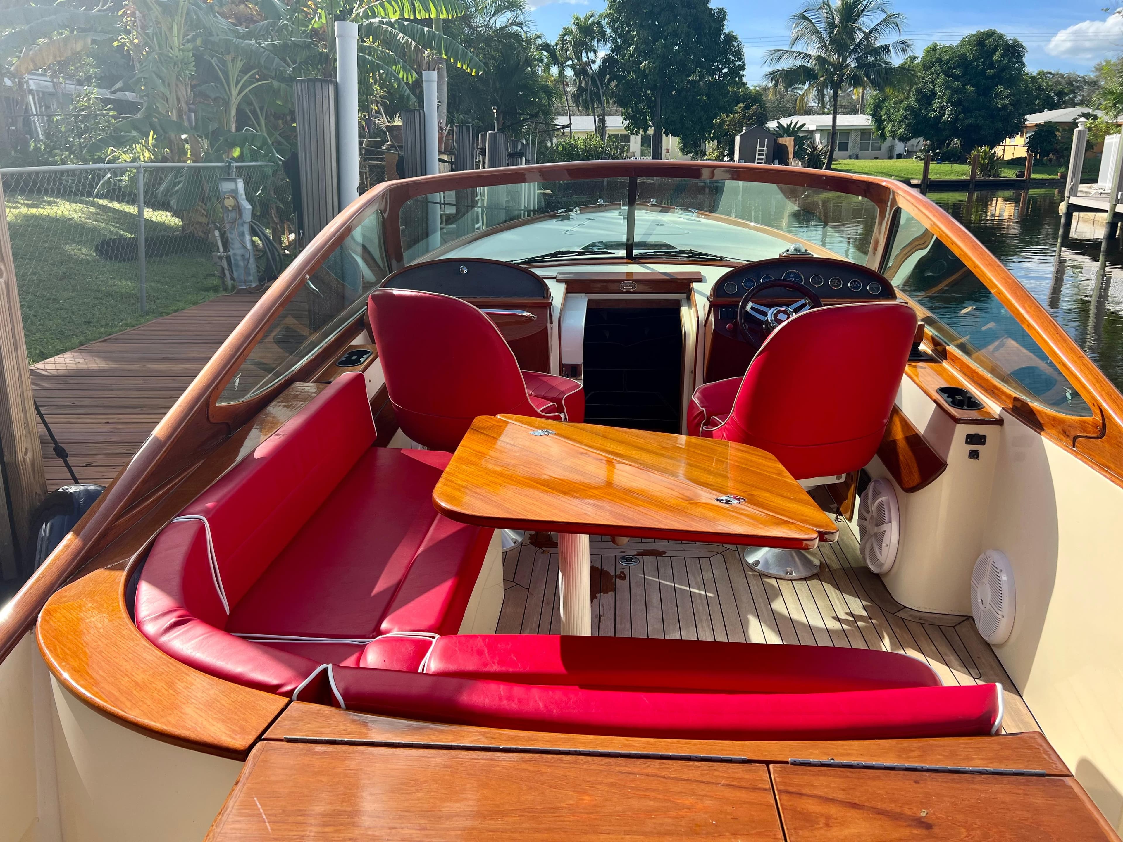 2004 Hinckley Talaria 29R boat with red seating and wooden accents.