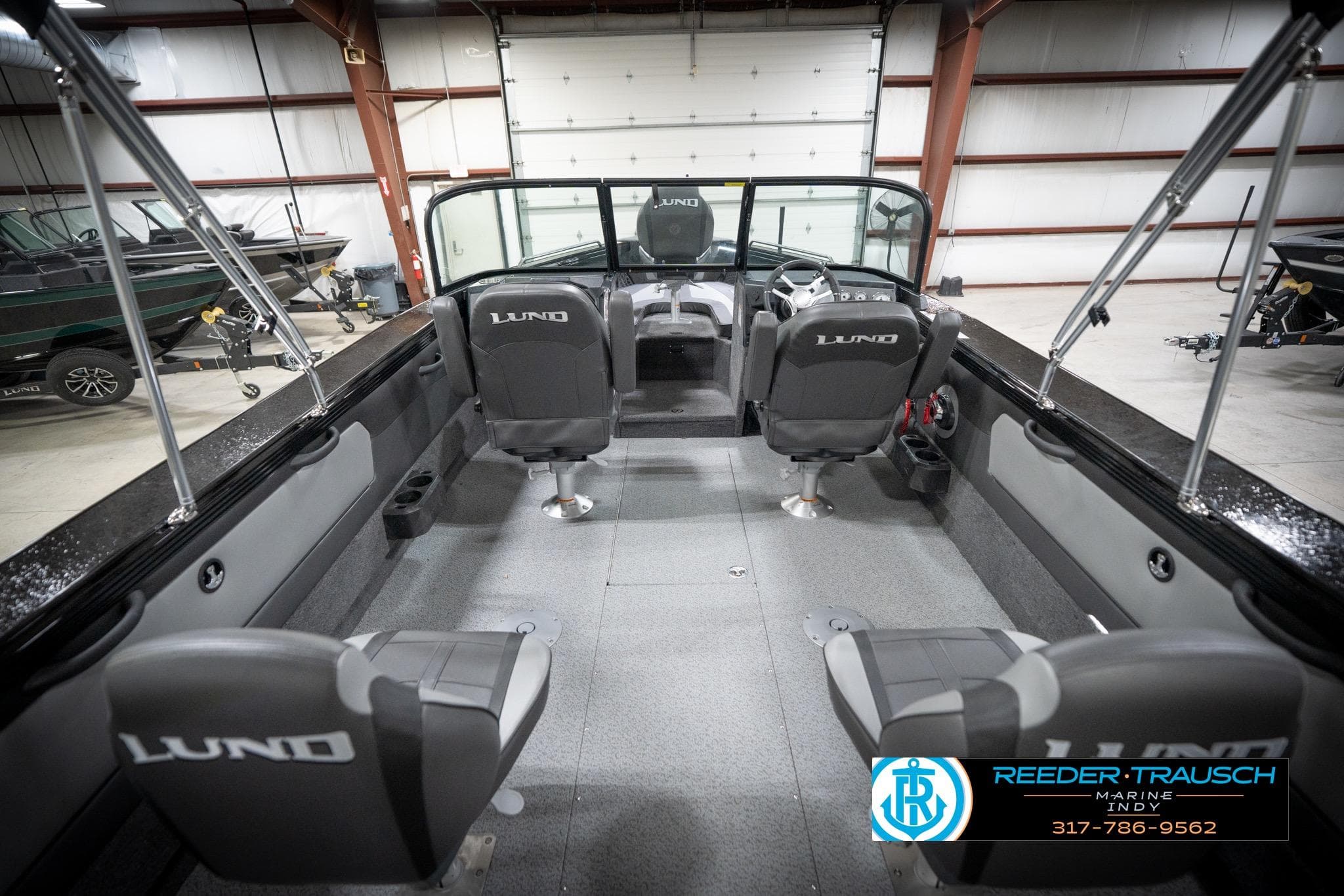 Interior of 2026 Lund 2275 Baron boat with seating and steering wheel in a showroom.
