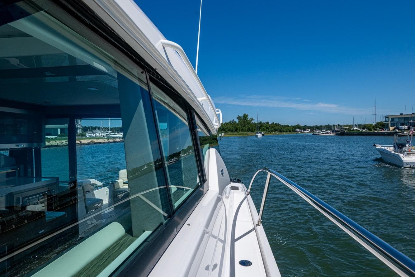 2020 Tiara Yachts C44 Coupe cruising on a sunny day near a marina.