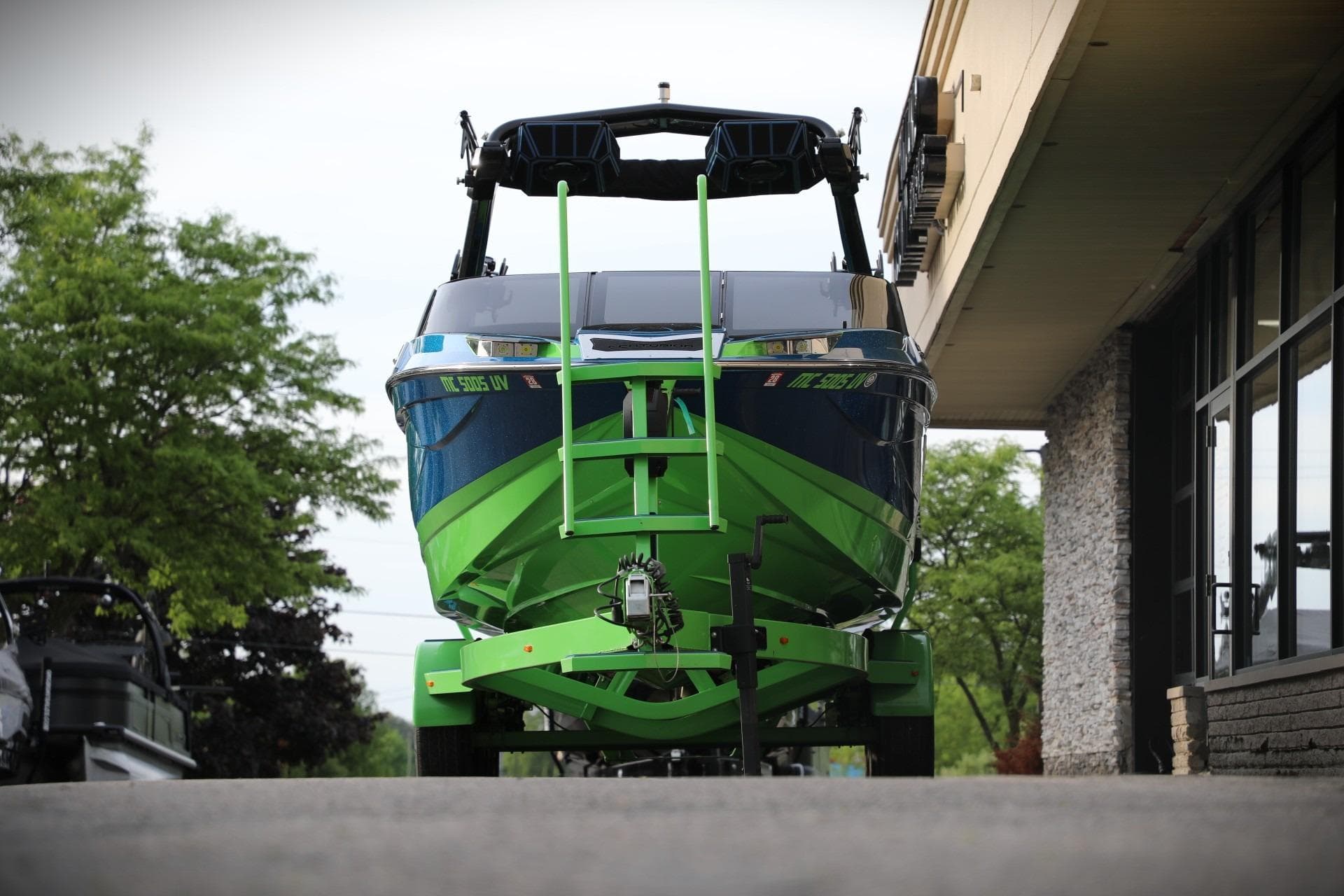 2022 Centurion Ri265 boat in vibrant green and blue, parked outside a building.