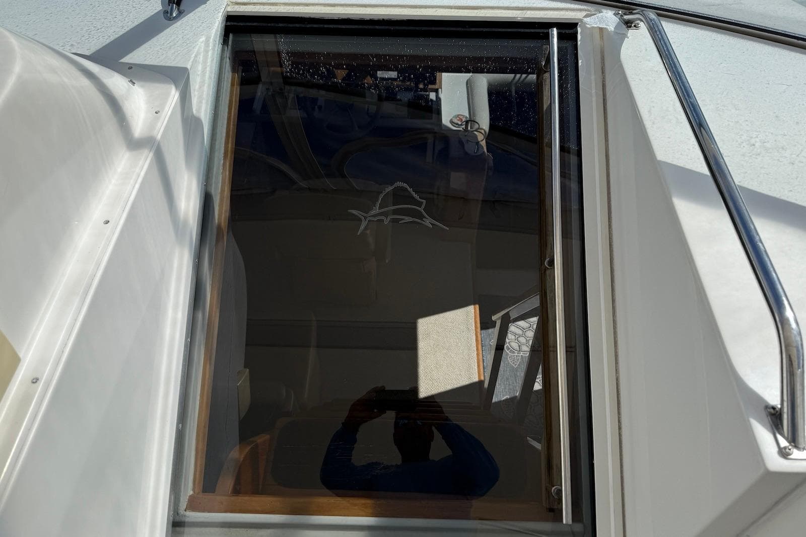 Glass hatch on 2004 Navigator 4800 yacht, reflecting sunlight and interior details.