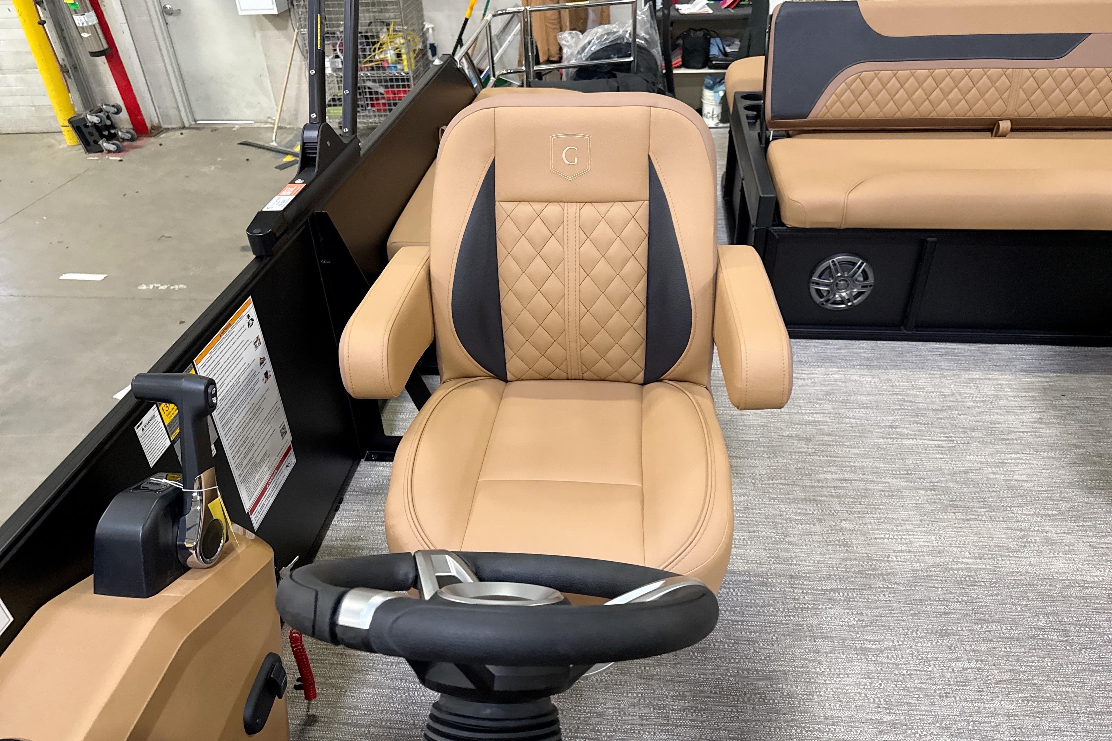 Captain's chair in 2026 Godfrey Sweetwater 22' Tritoon, featuring tan upholstery and steering wheel.
