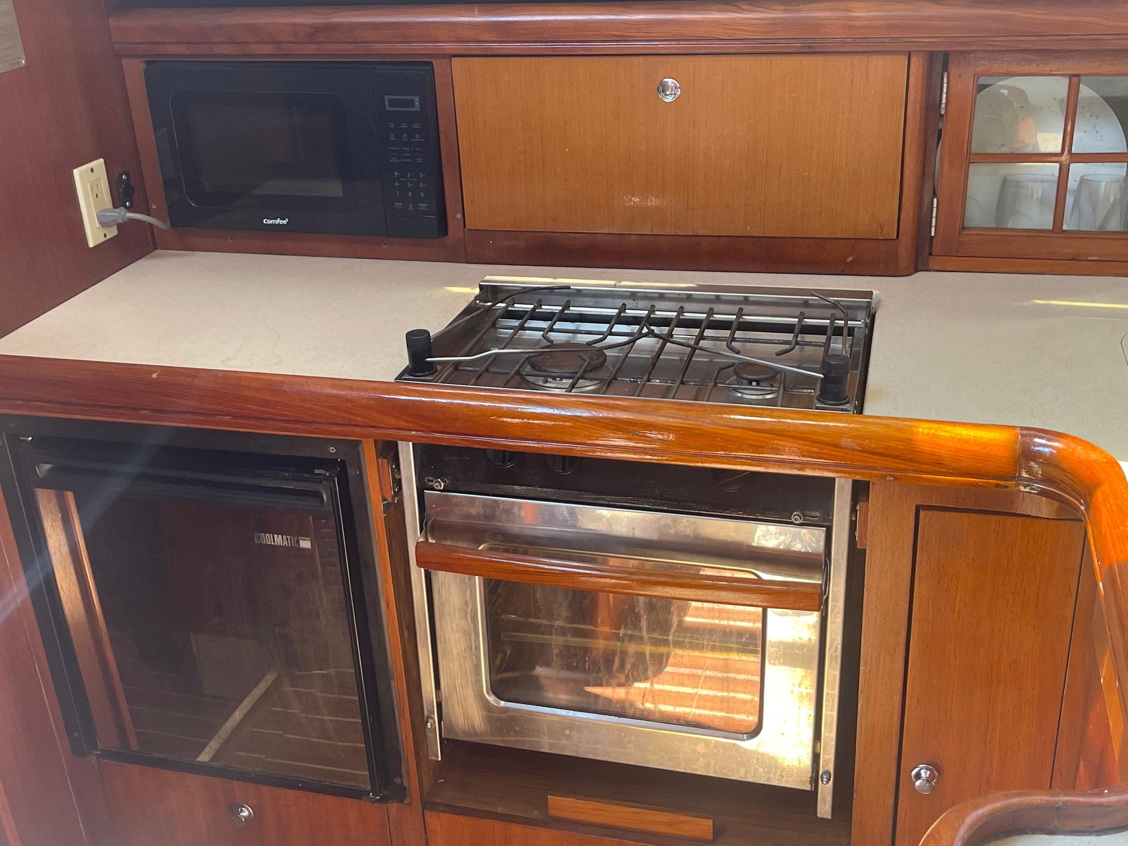 2004 Hunter 44 DS Deck Salon kitchen with stove, oven, microwave, and wooden cabinetry.
