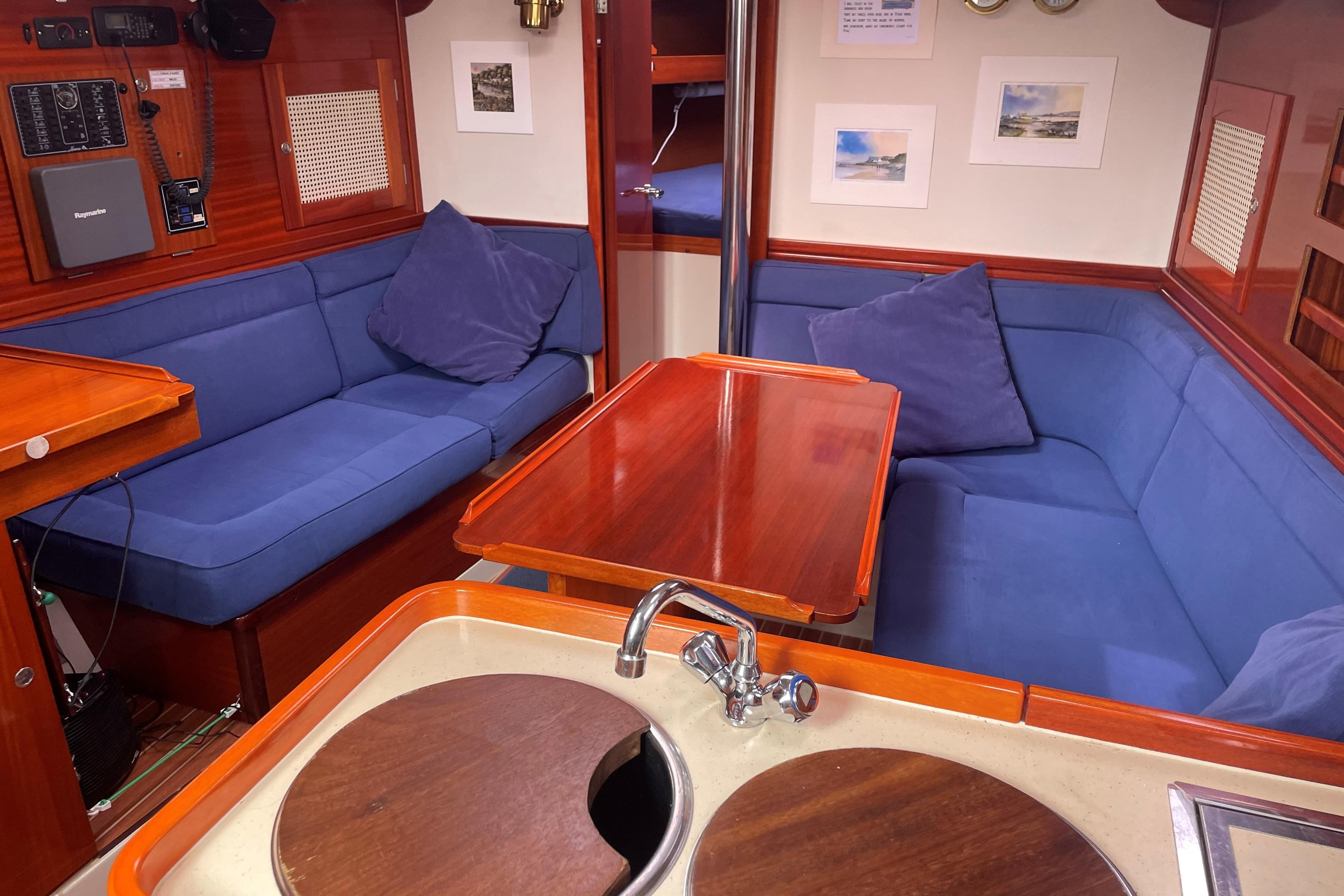 Interior of 2003 Hanse 341 yacht with blue seating and wooden table.