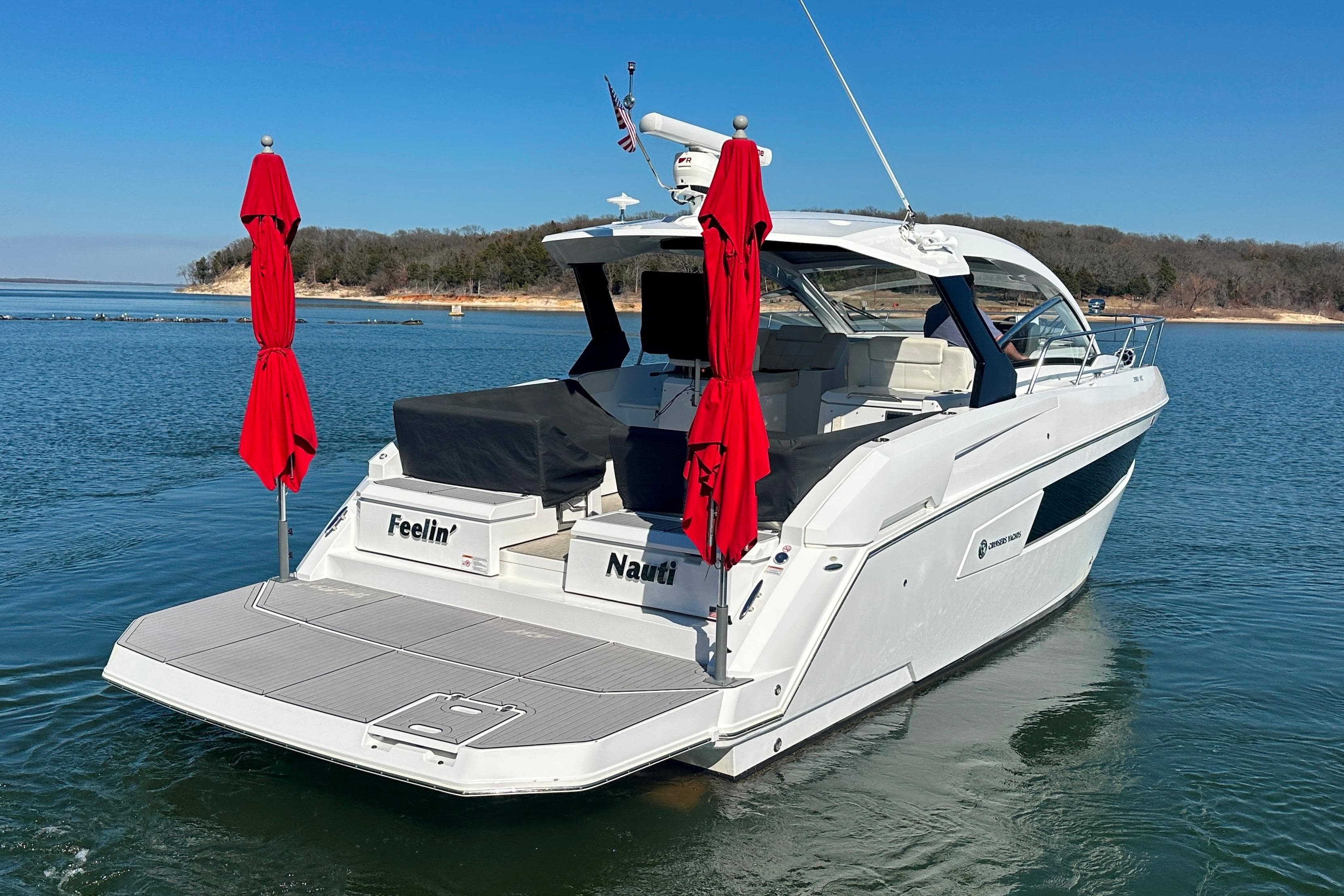 2021 Cruisers Yachts 390 Express Coupe on serene lake with red umbrellas.