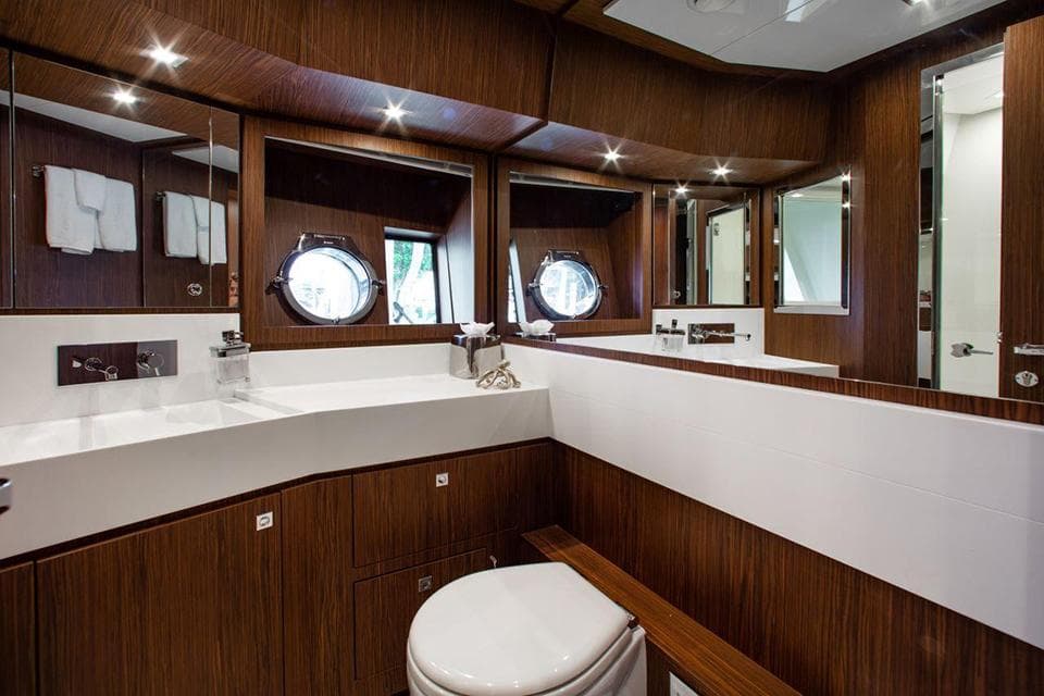 Luxurious bathroom on the 2017 Riva 88 Domino Super yacht with wood paneling and porthole windows.