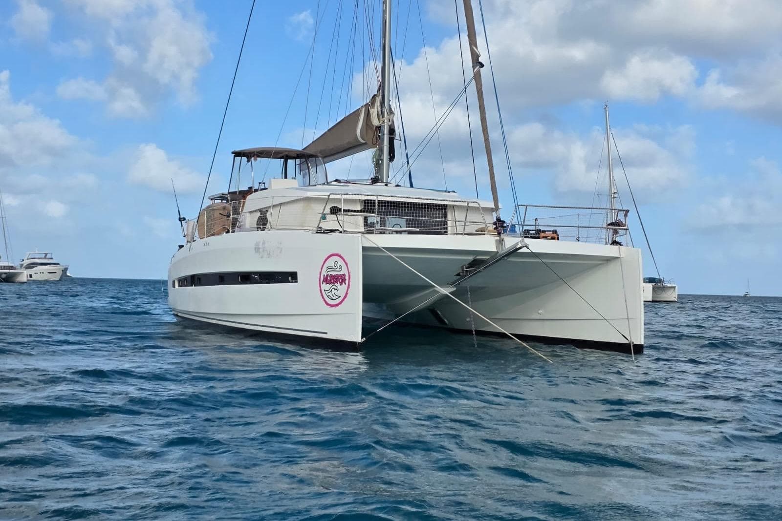 A 2016 Bali 4.5 catamaran anchored in calm blue waters under a partly cloudy sky.