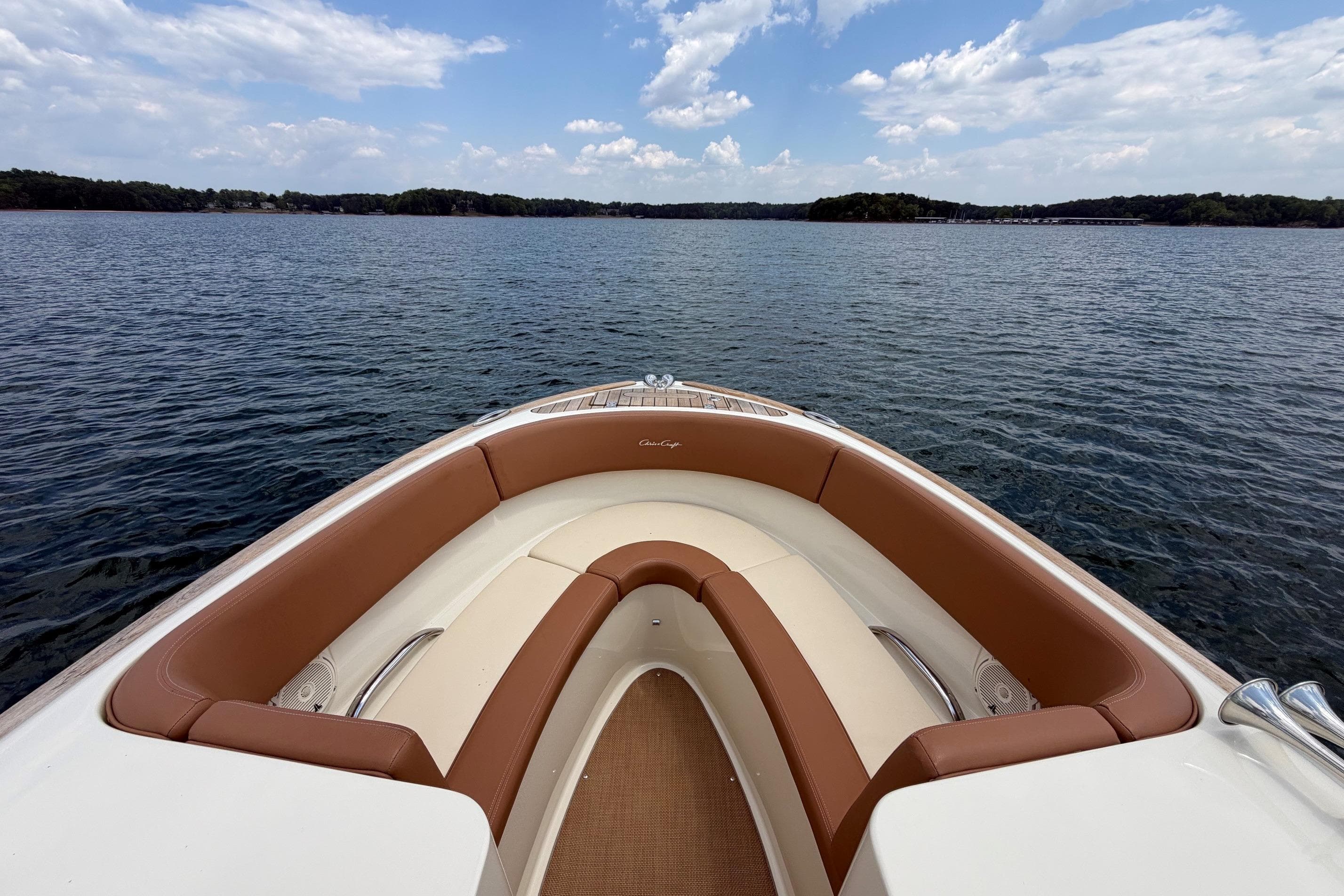 2017 Chris-Craft Launch 25 boat interior with brown seating, on a calm lake under a blue sky.
