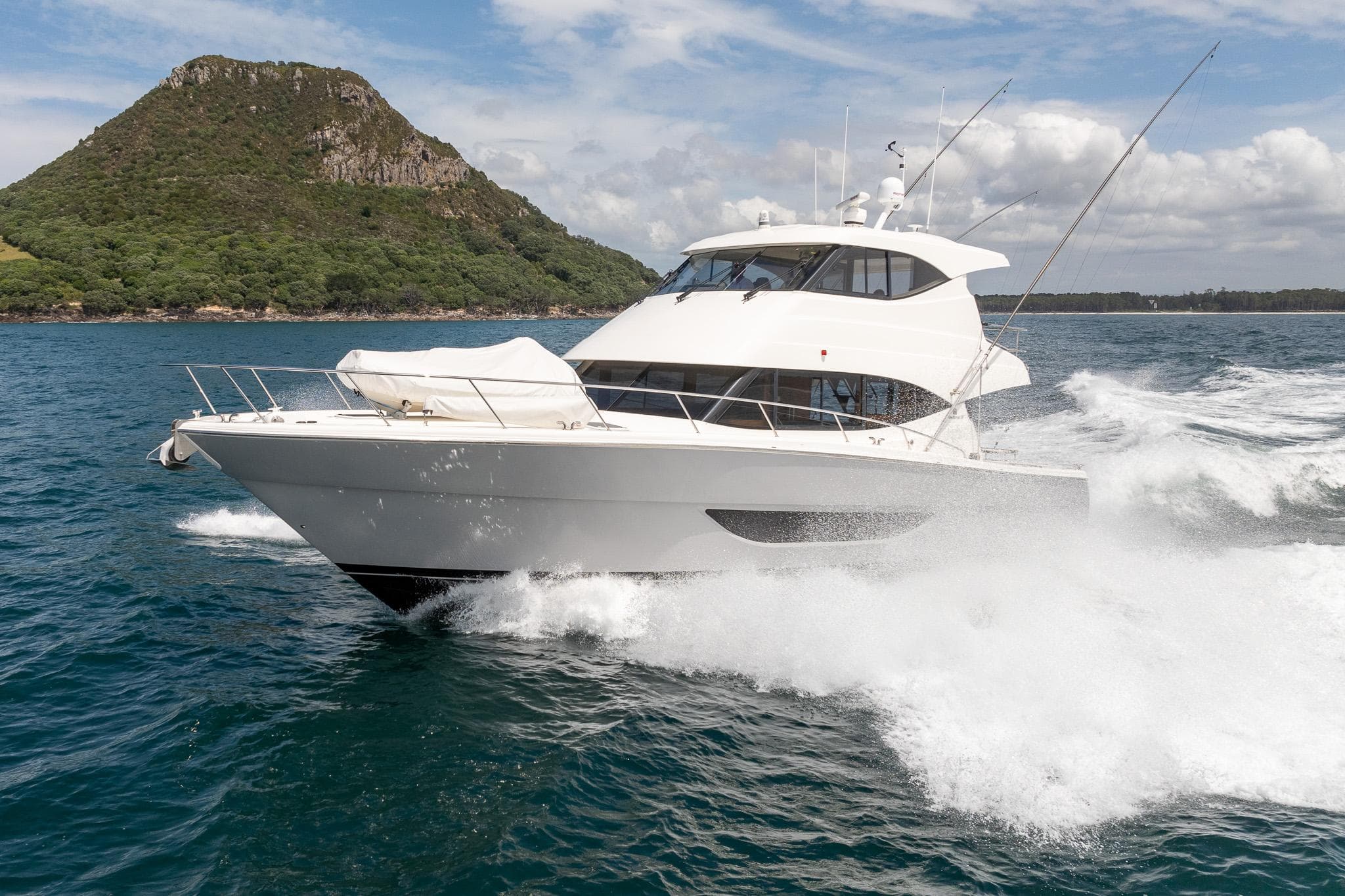 2021 Maritimo M51 yacht cruising on open water near a lush island.