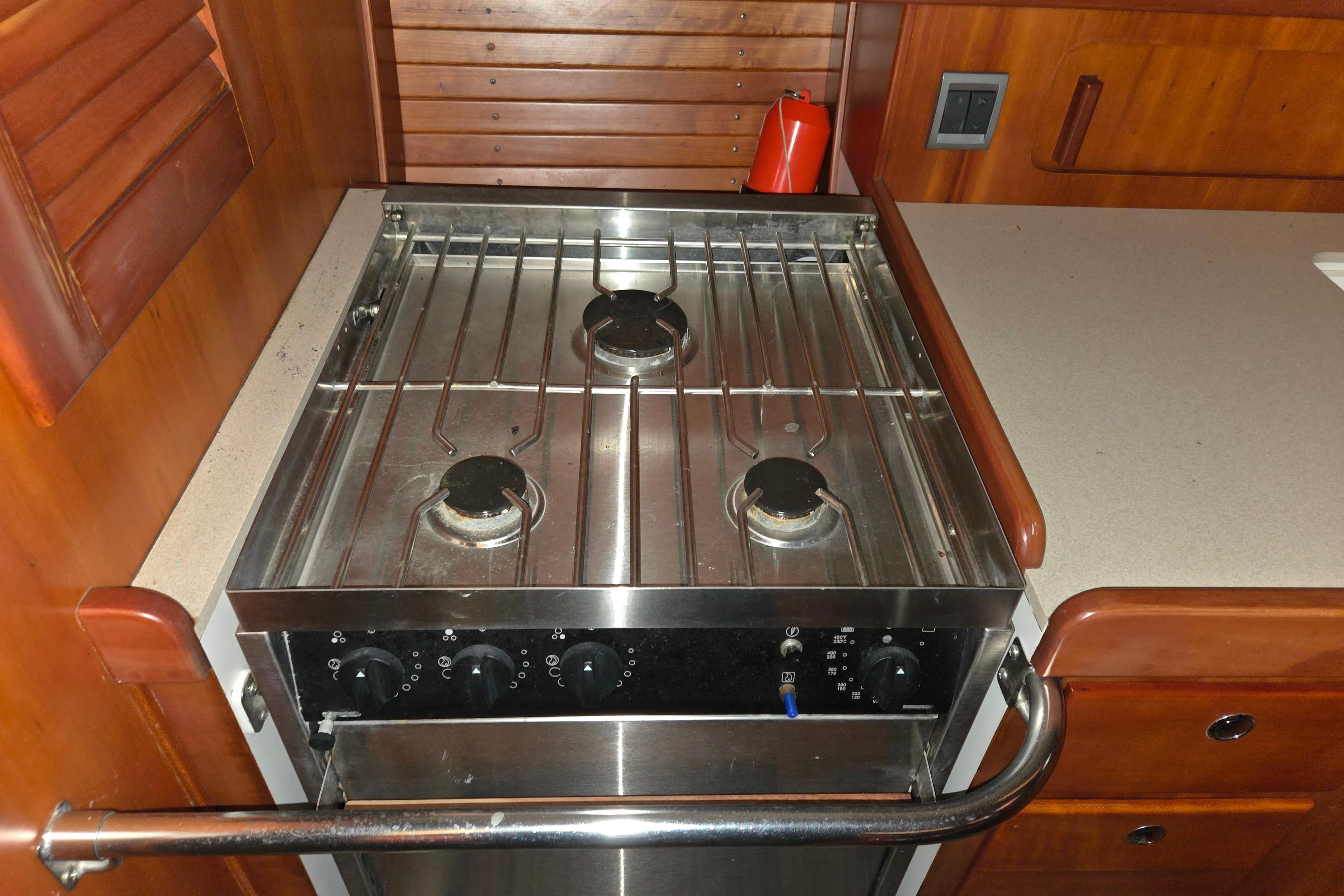 Galley stove in 2000 J Boats J/46 yacht, featuring three burners and wooden cabinetry.