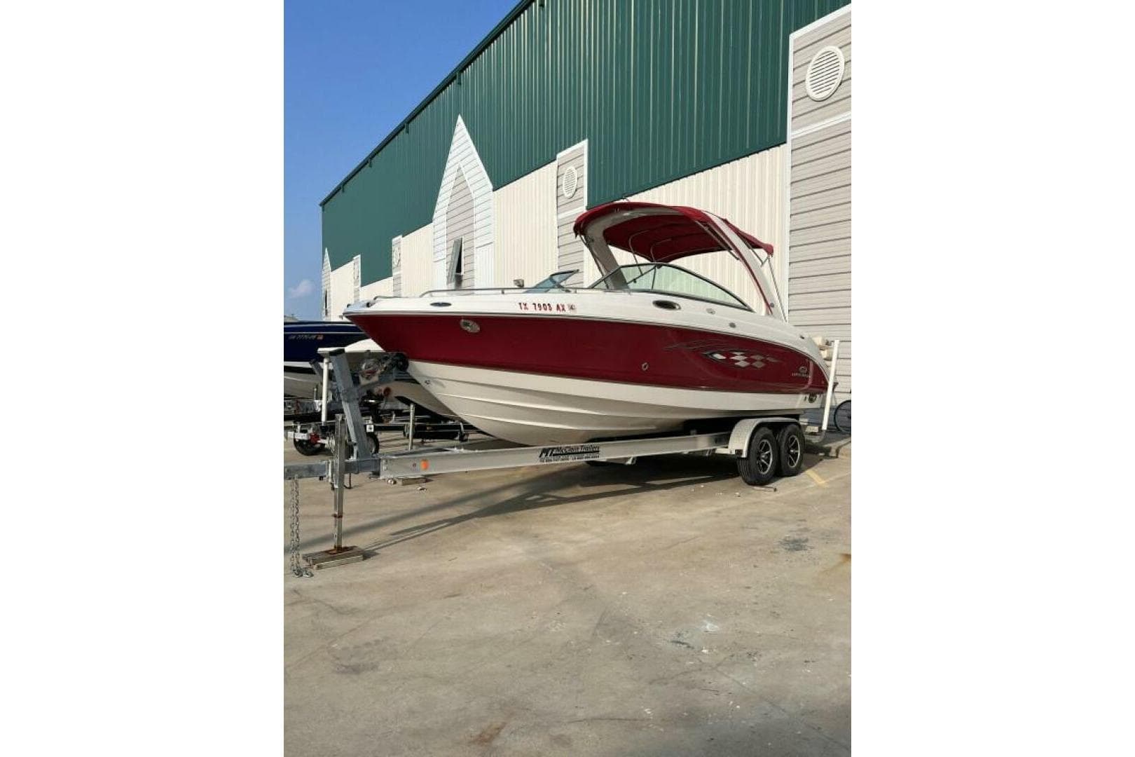 2006 Chaparral 256 SSi boat on trailer, parked outside a large building.