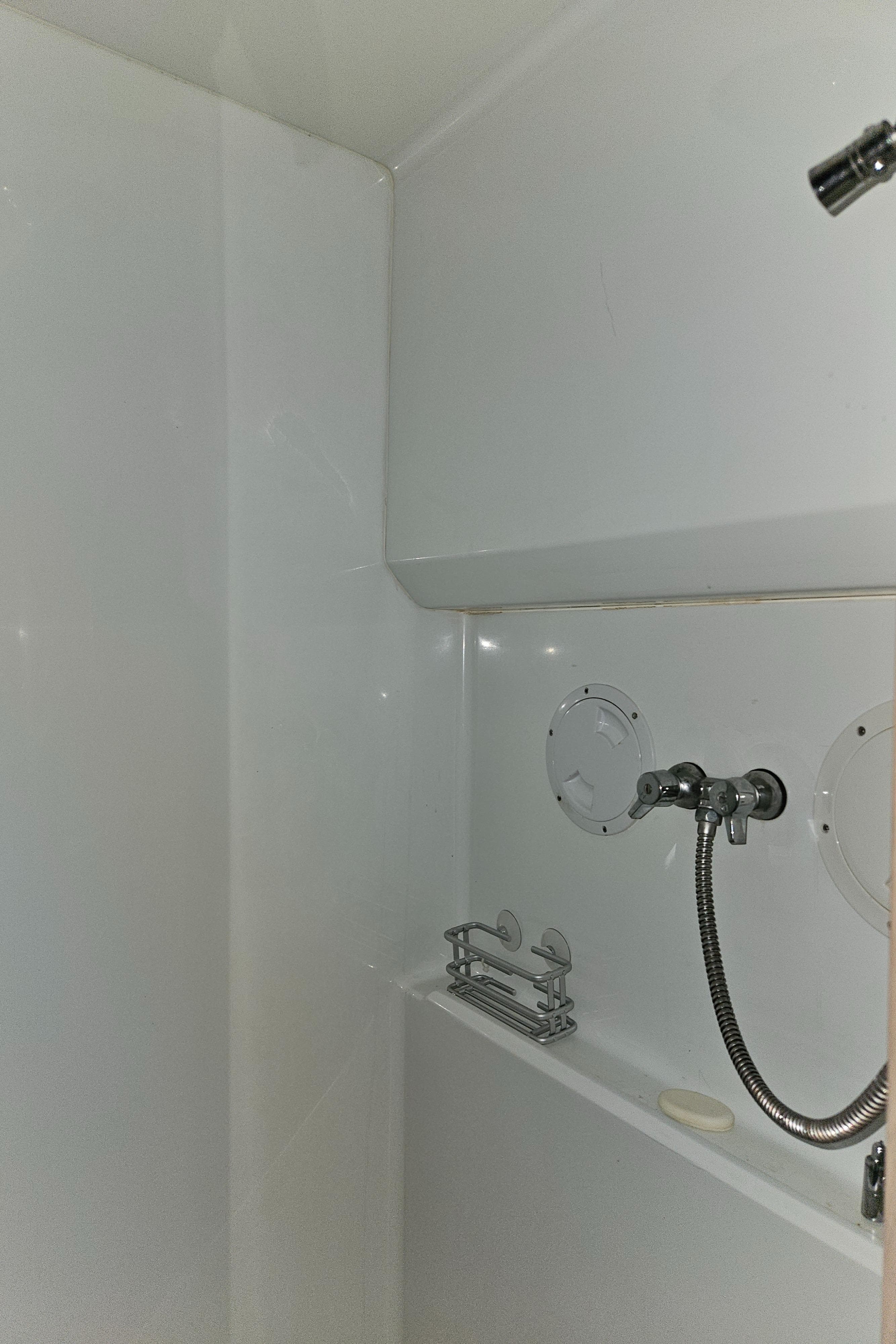 1991 Tollycraft Euro Sport Sedan shower area with white walls and chrome fixtures.