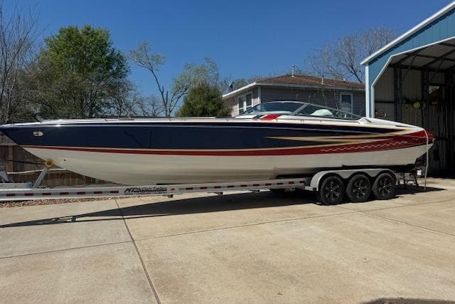 2007 Formula 353 FASTech speedboat on trailer, parked outdoors near a garage.