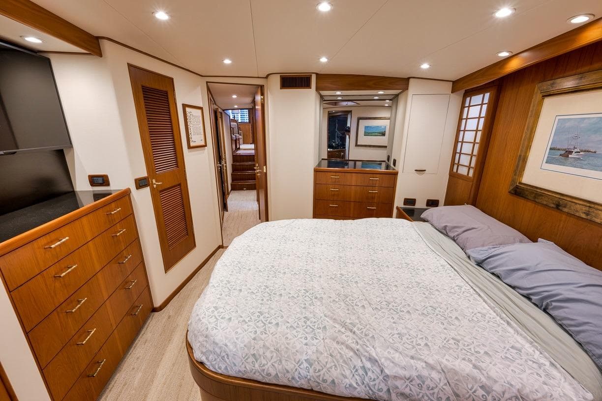 Luxurious 2001 Rybovich Sportfisherman yacht bedroom with elegant wood finishes and cozy bedding.