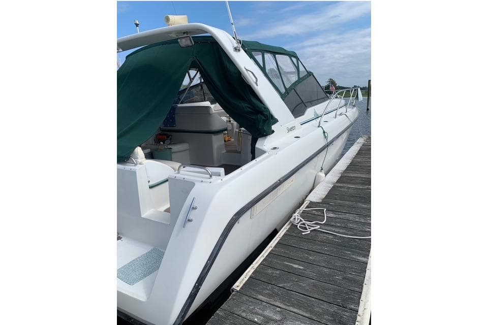 1993 Silverton Express boat docked, featuring green canopy and sleek white design.
