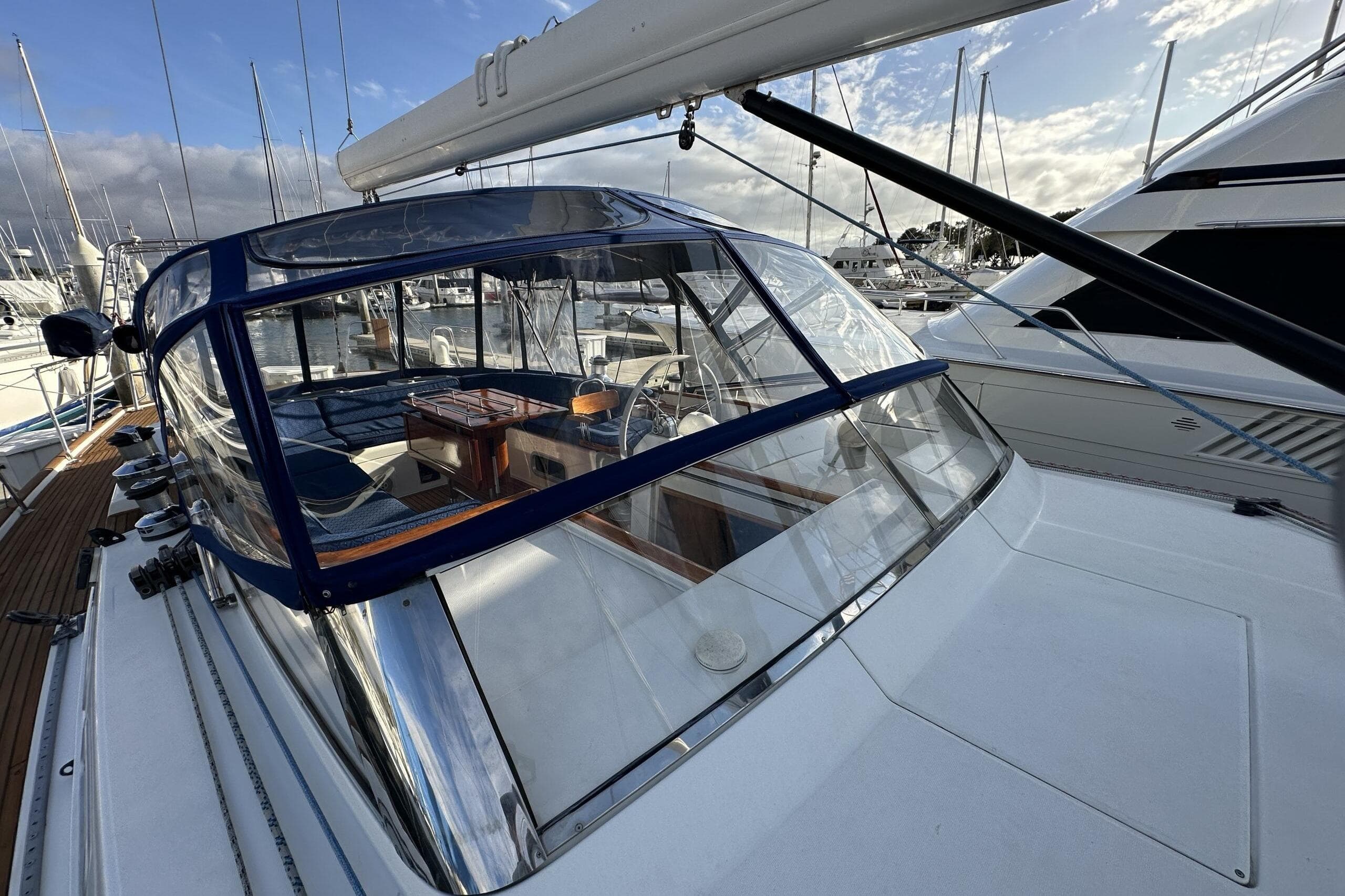 2003 Beneteau 57 yacht with blue canopy, docked at marina under cloudy sky.