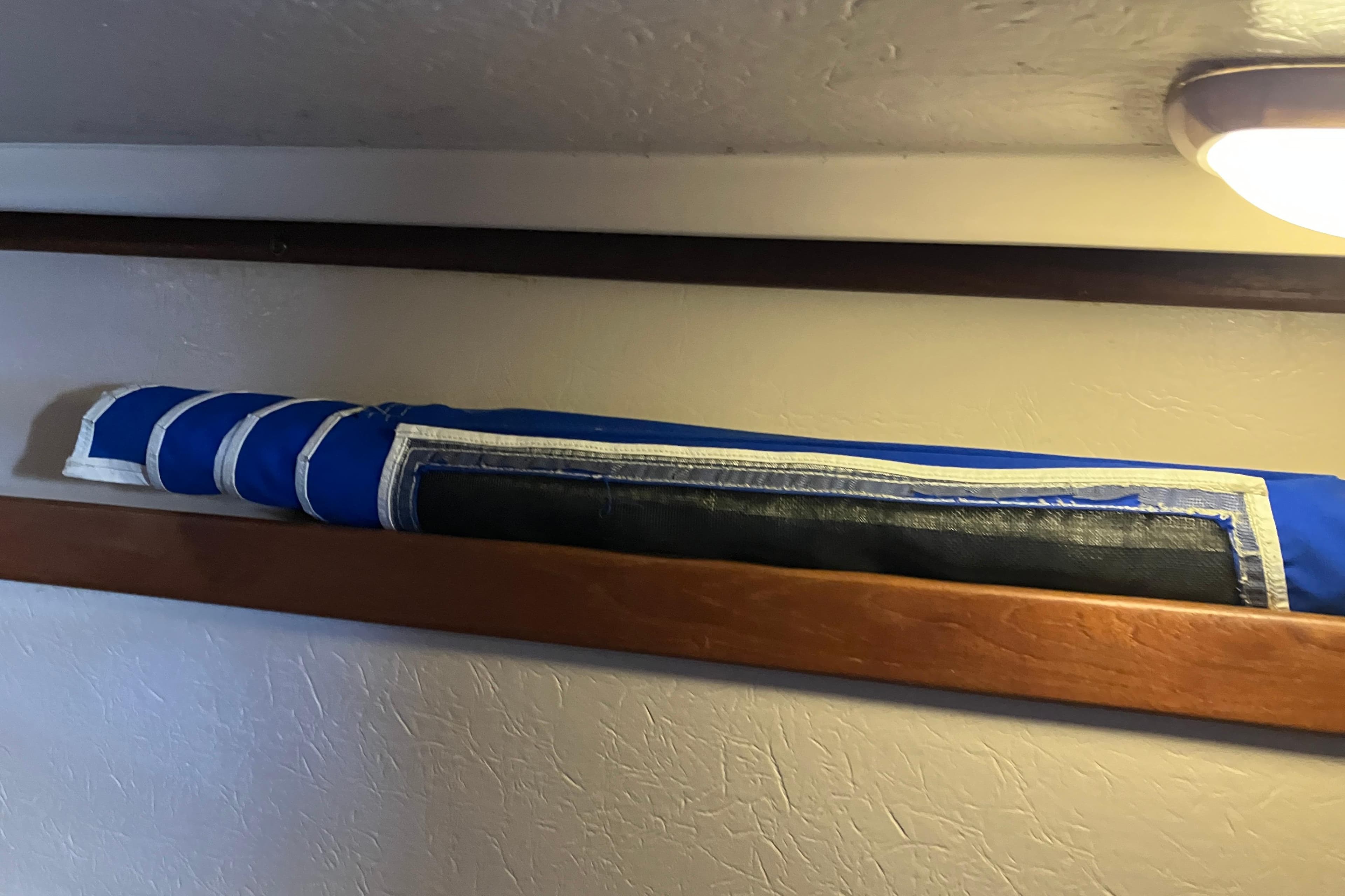 Rolled blue sail stored on a wooden shelf inside a 1985 Catalina 30 boat.