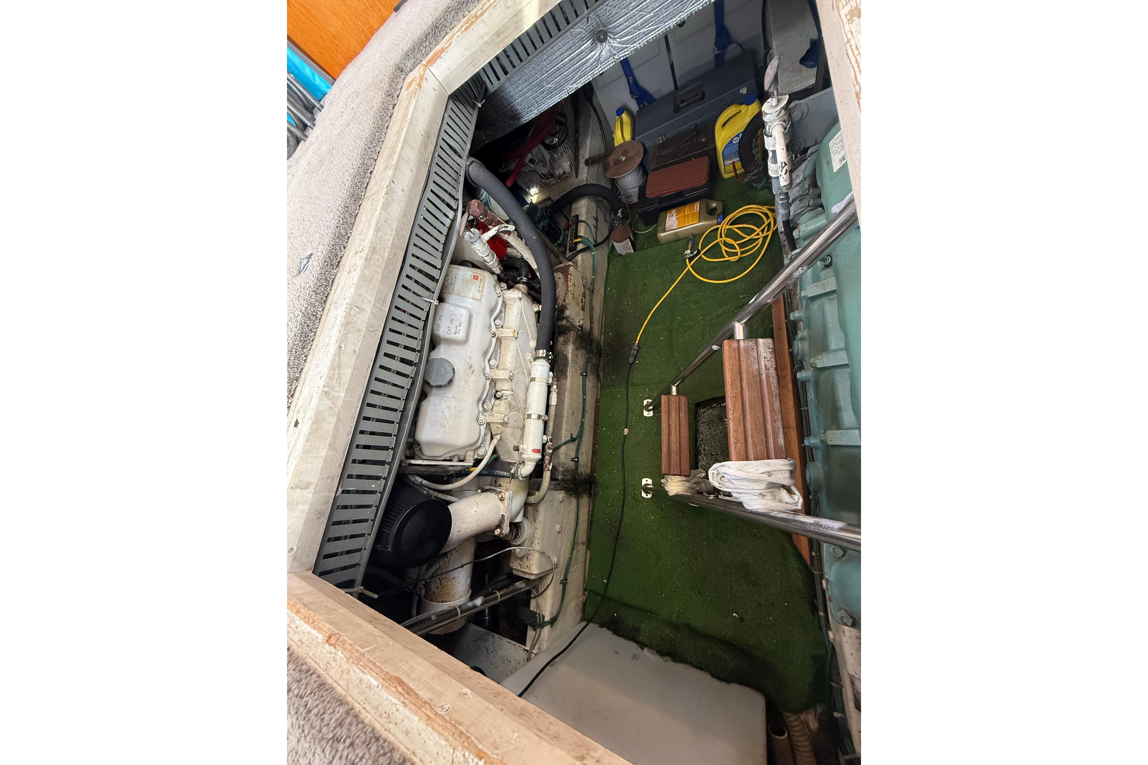 Engine room of a 1990 Cooper Prowler boat, featuring mechanical components and storage items.