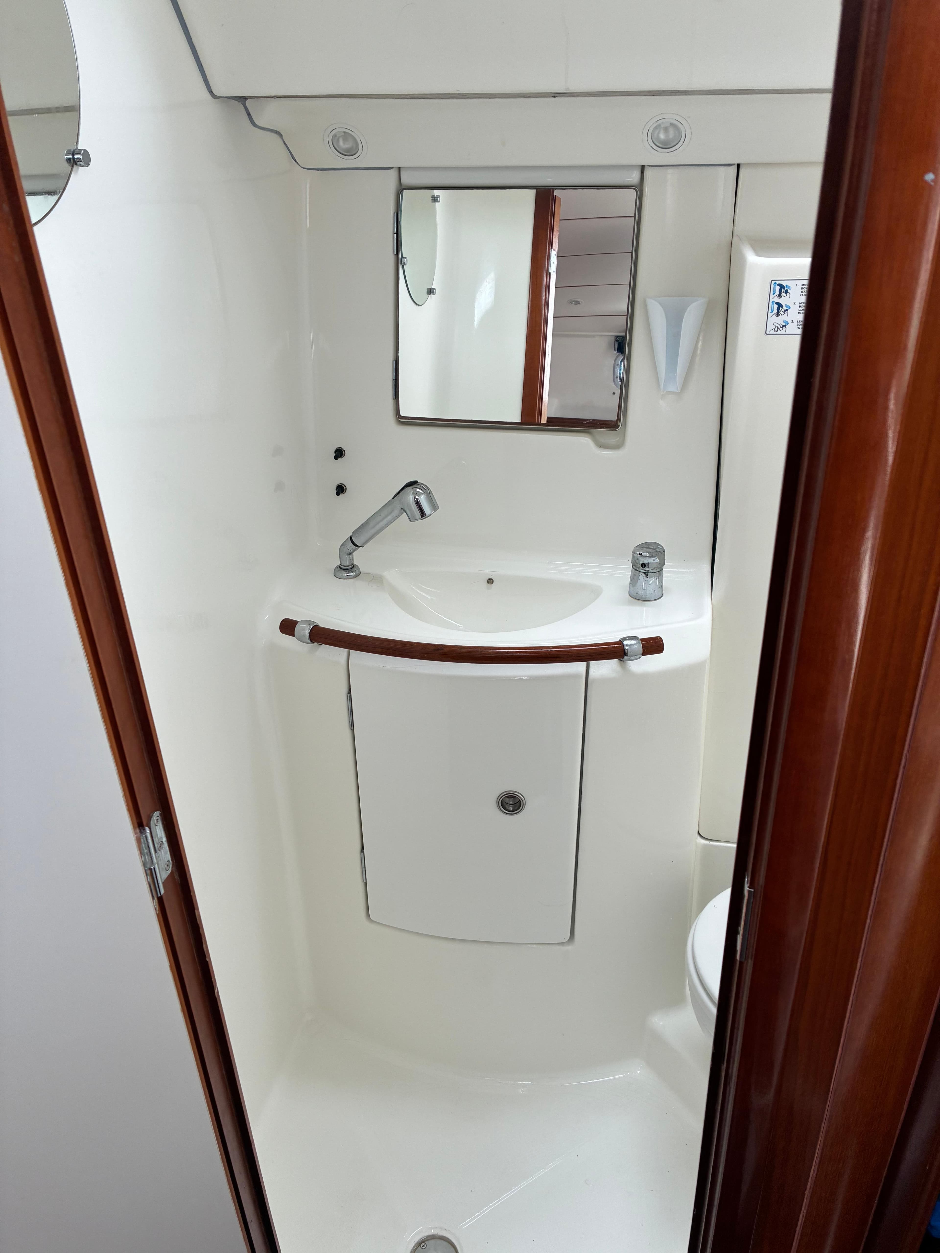 Compact bathroom in a 2003 Beneteau Oceanis Clipper 393 yacht, featuring a sink and mirror.