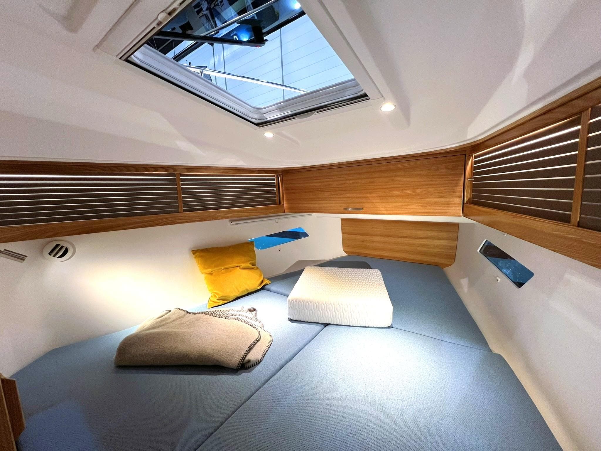 Cozy cabin interior of 2027 Dragonfly 36 sailboat with skylight and cushions.