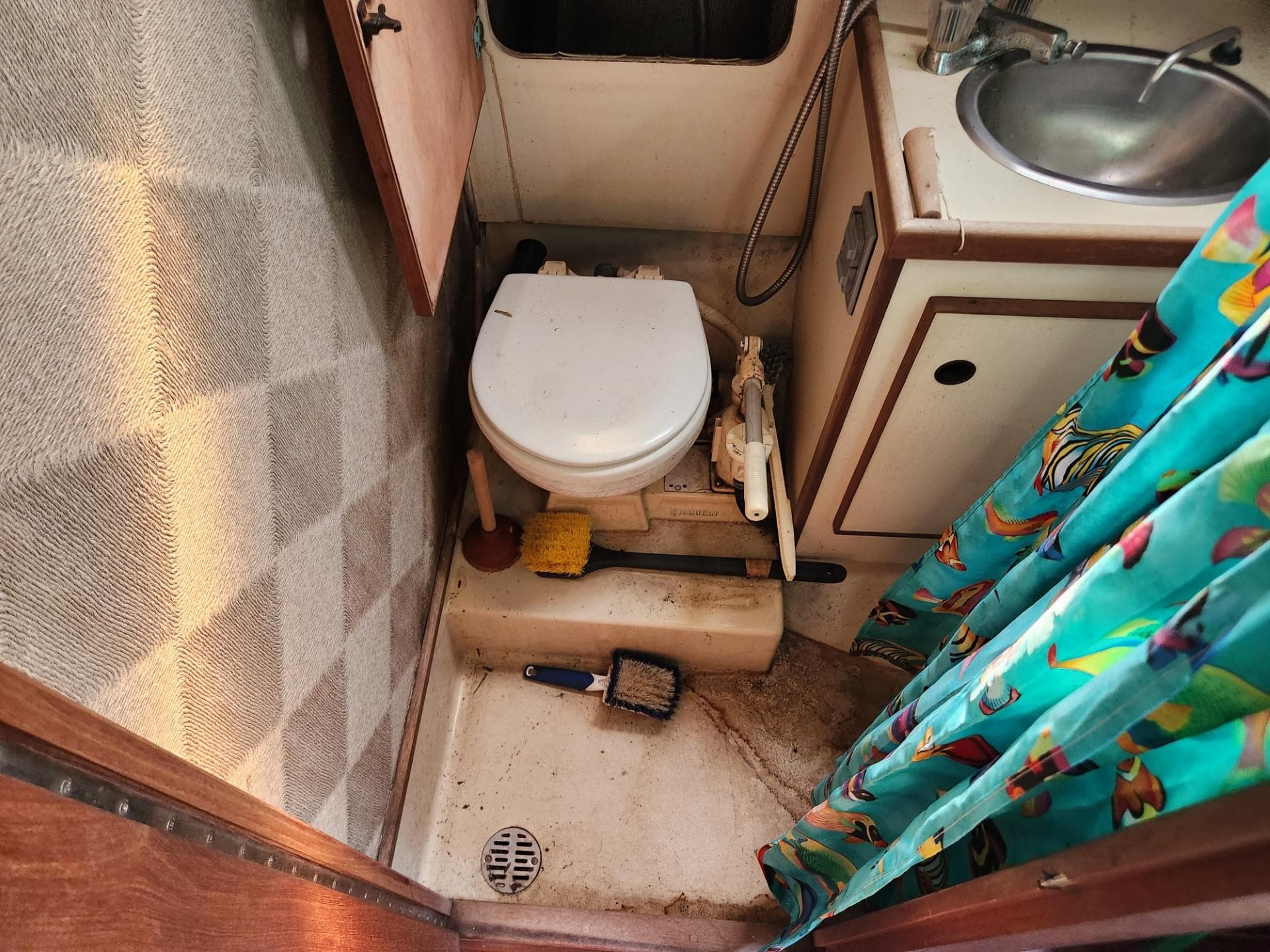1984 S2 9.2 boat bathroom with toilet, sink, and cleaning supplies.