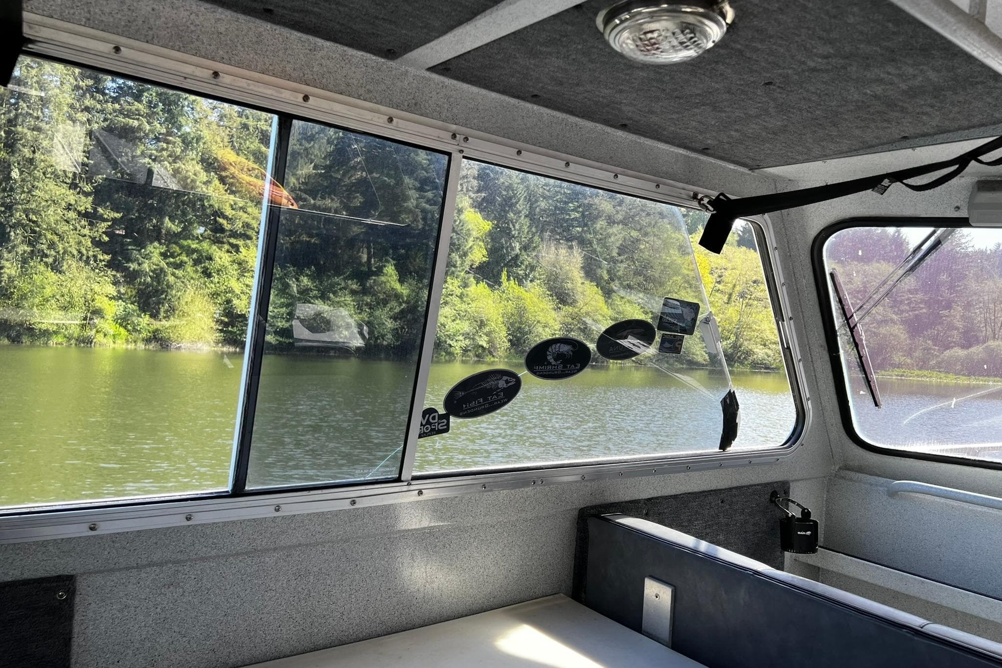 Interior view of 1998 Maxweld Cuddy Hardtop boat with scenic lake and forest outside.