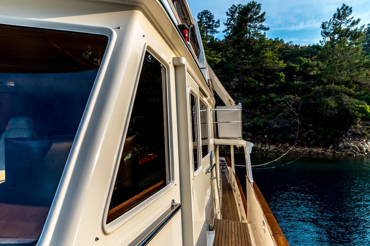 Side view of a 2004 Fleming 75 yacht near a forested shoreline.