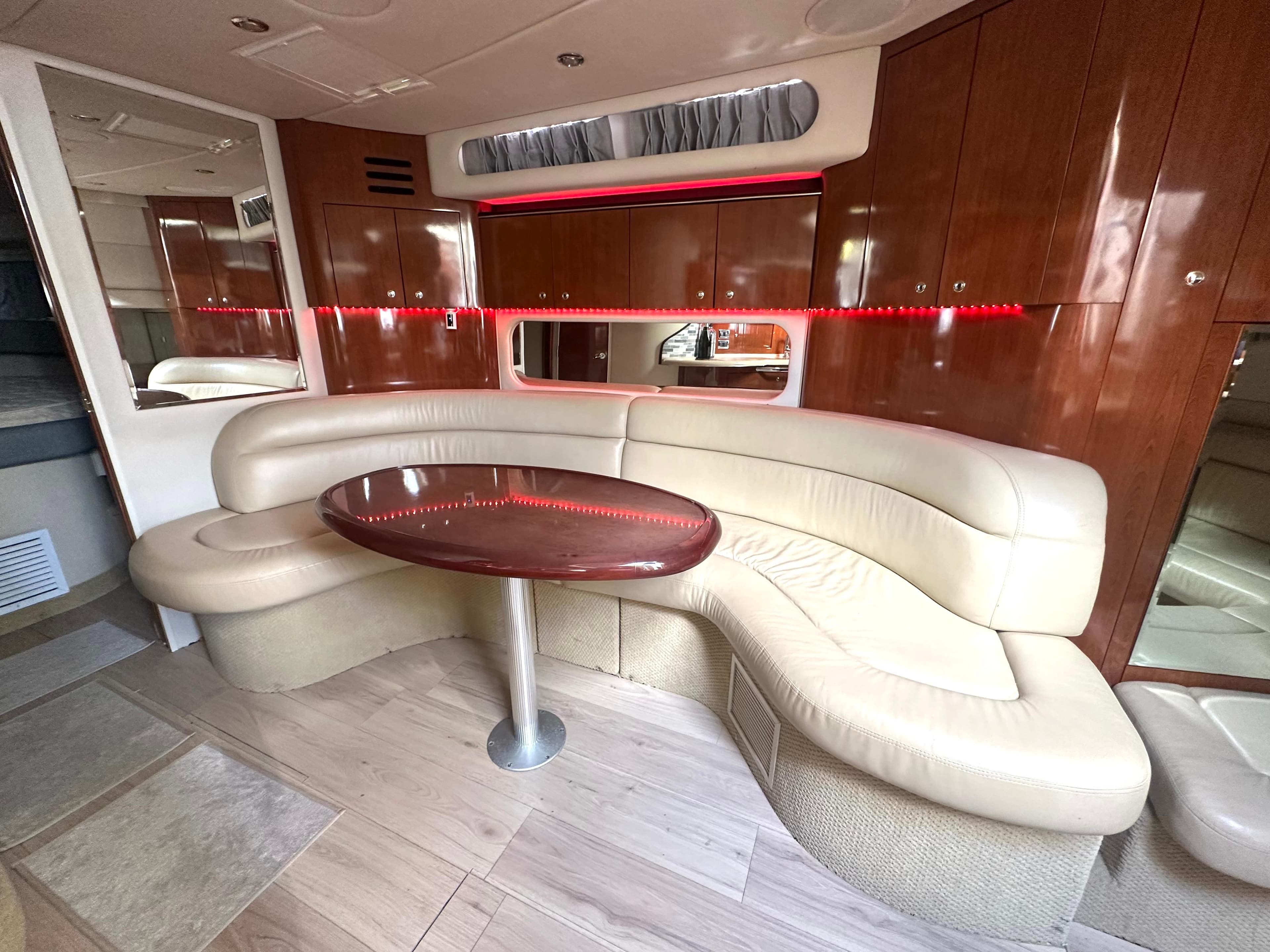 Luxurious 2003 Sea Ray 380 Sundancer interior with curved leather seating and wooden table.