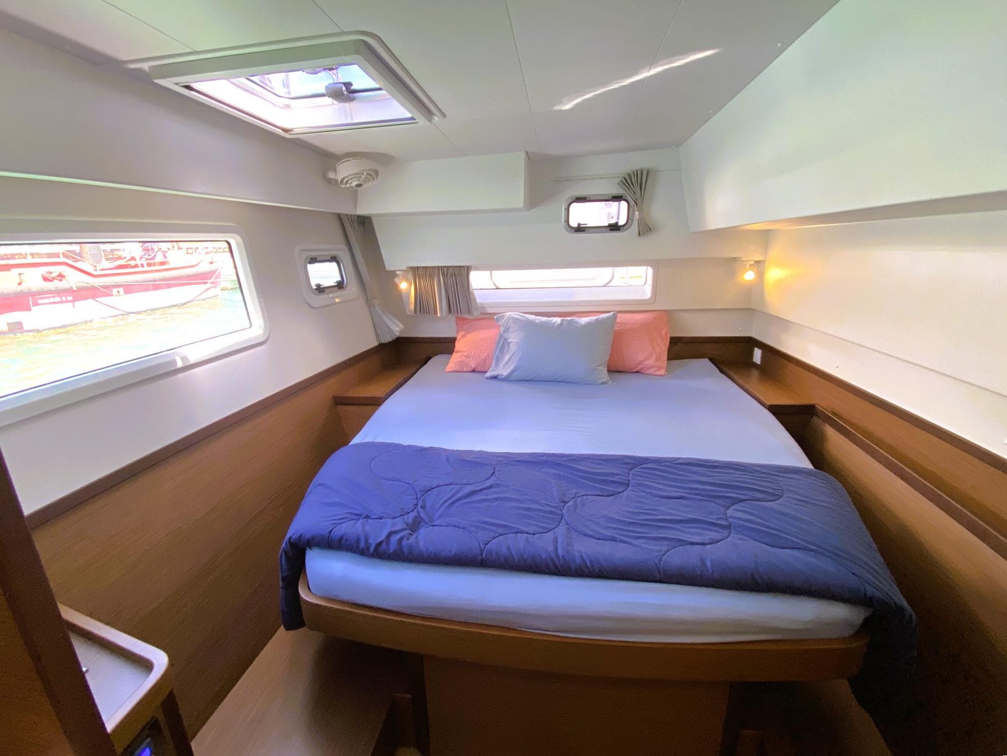 Cozy bedroom in 2021 Lagoon 42 yacht with double bed, windows, and soft lighting.