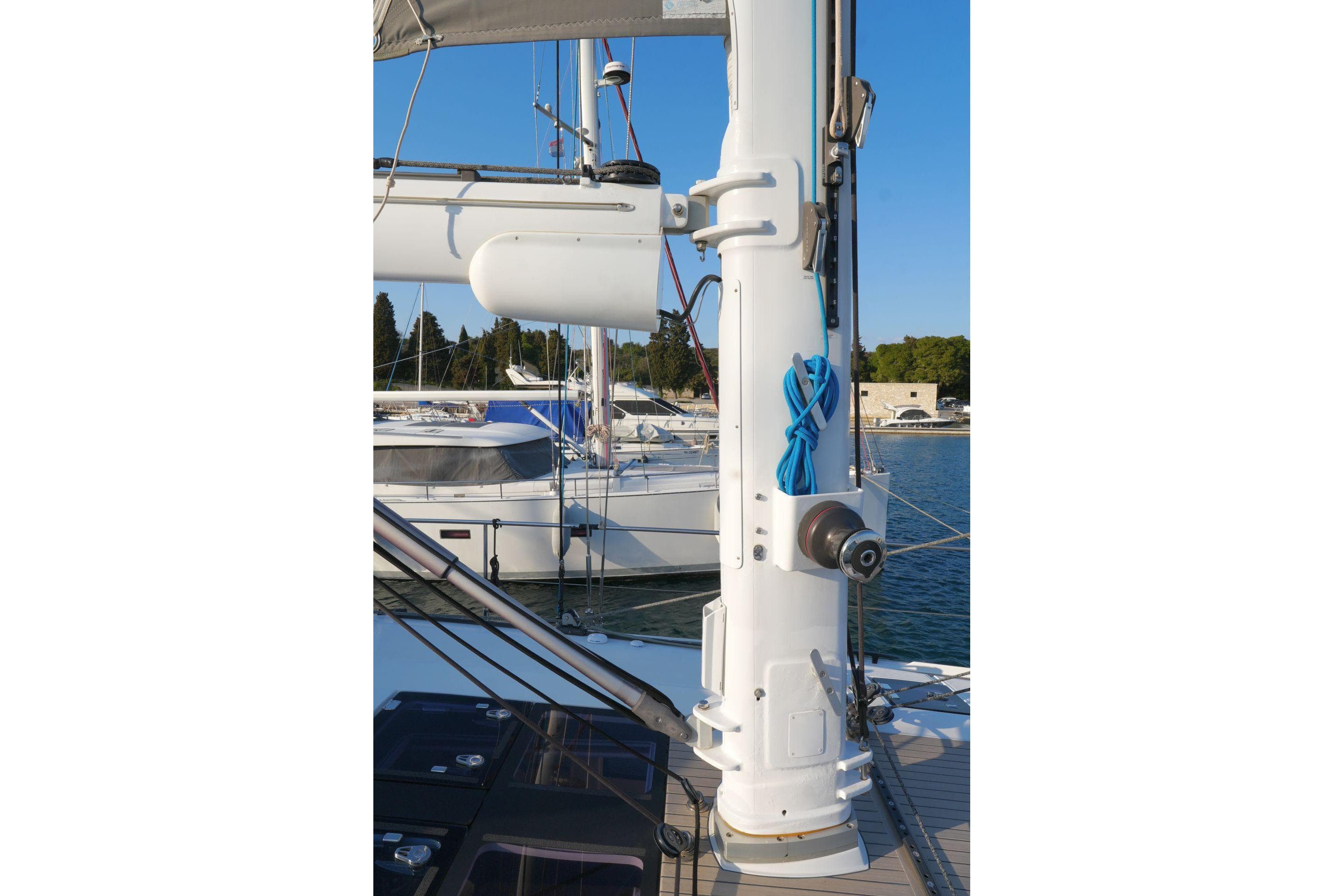Sailboat mast on 2017 Amel 50 yacht, docked in marina with clear blue sky.