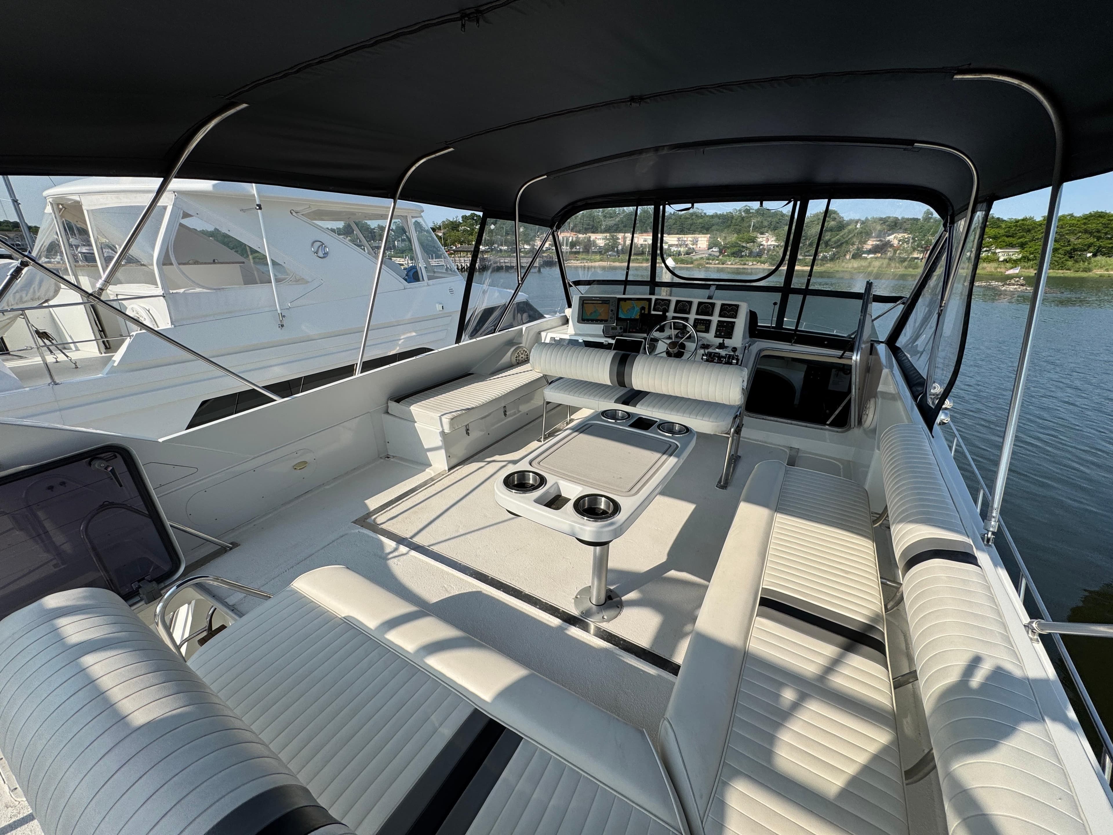 1989 Birchwood 62 Cockpit Motor Yacht interior with seating and helm, docked by the water.