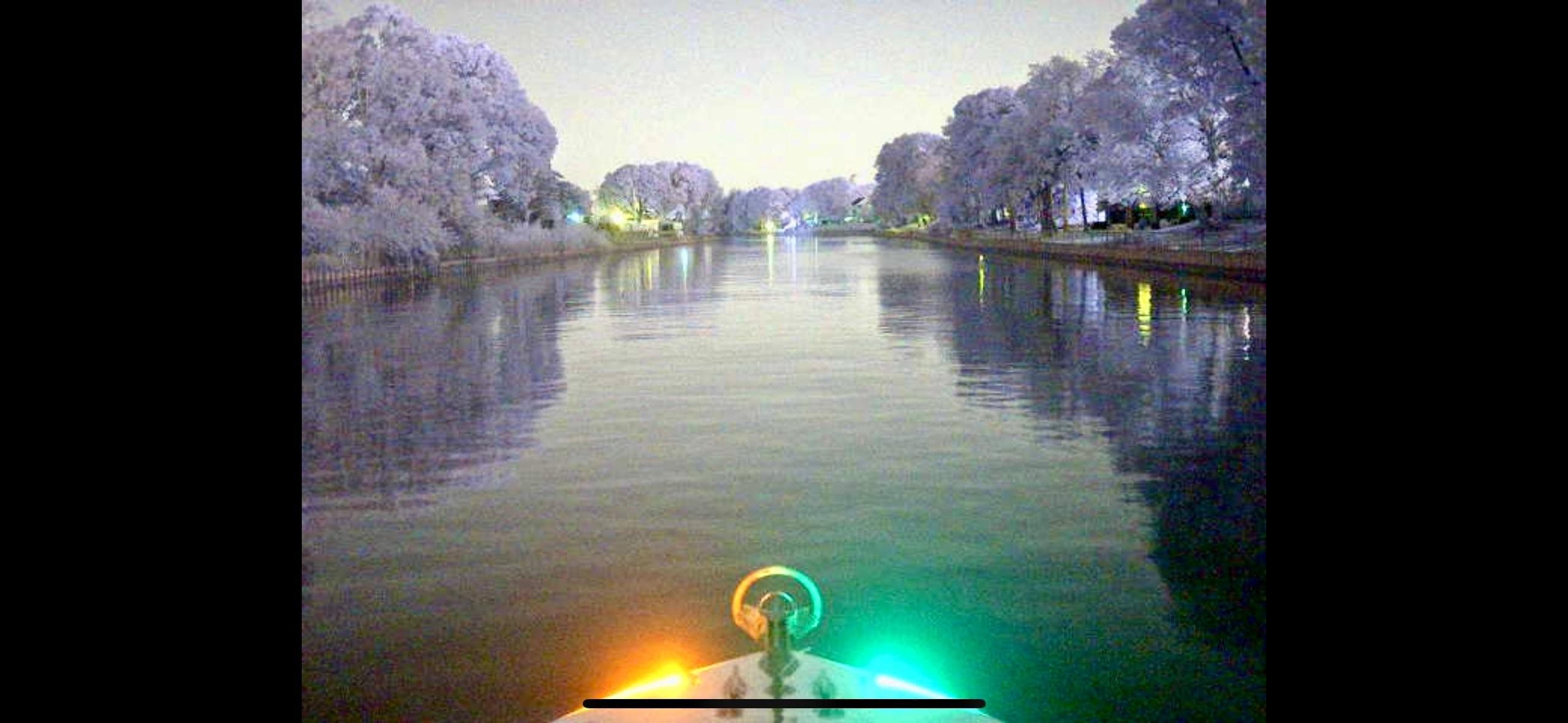 2004 Contender 31 Fish Around boat navigating a serene, tree-lined waterway at night.