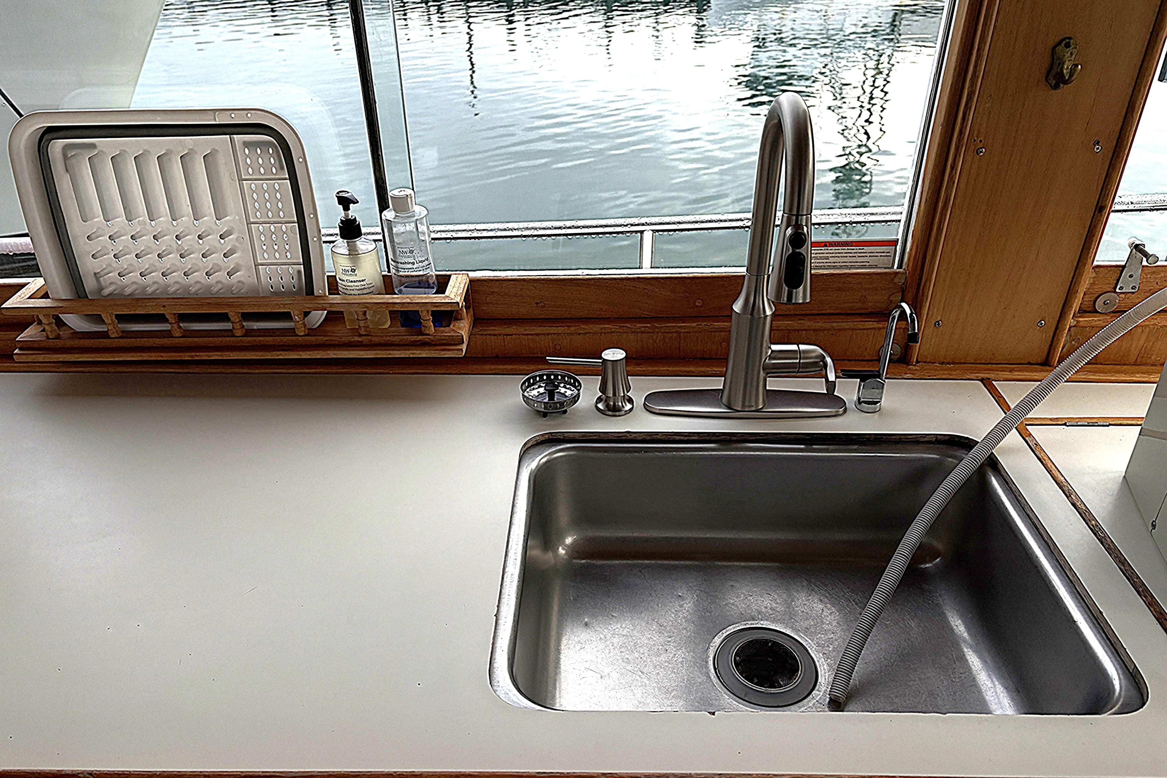 1984 Grand Banks Classic kitchen sink with modern faucet and dish rack by window.