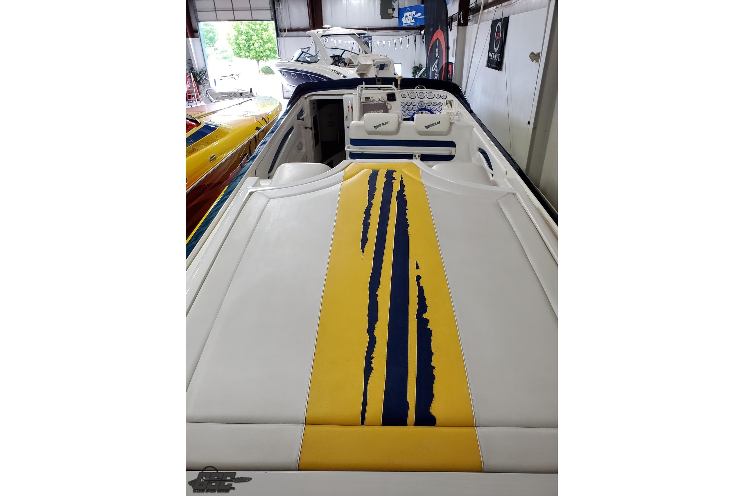 2001 Hustler 50 Monster boat with yellow and blue stripe design in a showroom.