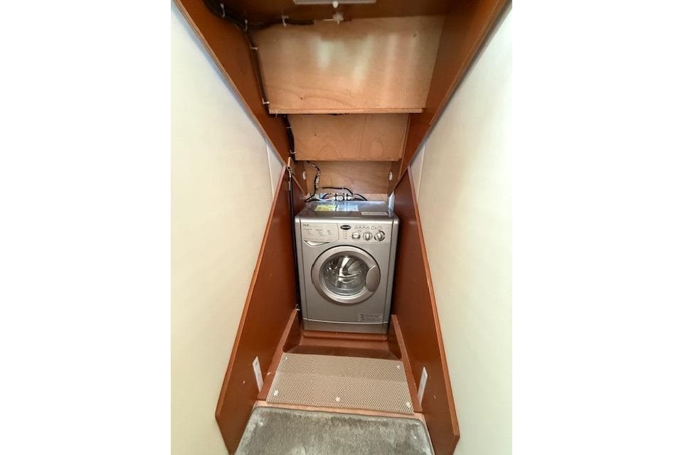 Compact laundry area with a washing machine inside a wooden cabinet, Prestige 500, 2015 model.