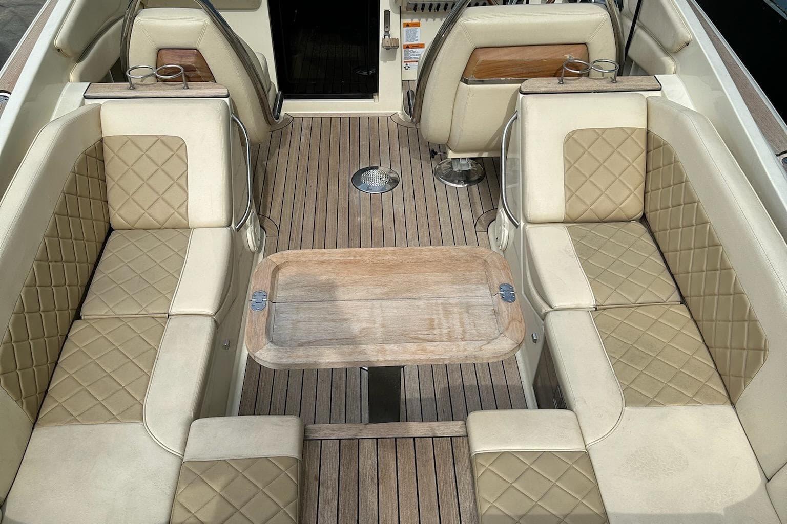 2019 Chris-Craft Corsair 30 interior with beige quilted seating and wooden deck.