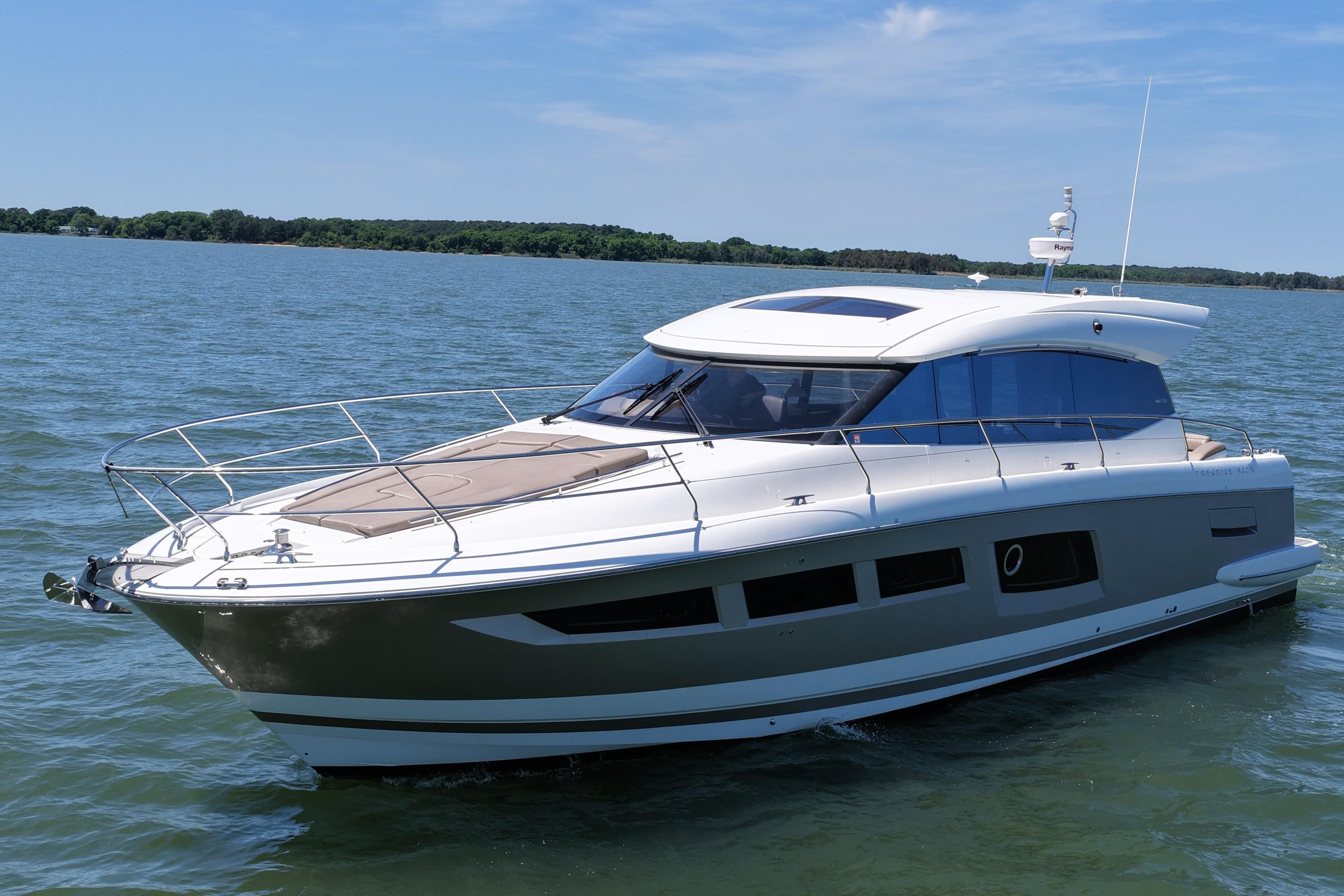 Luxury 2015 Prestige 500S yacht cruising on a serene lake under a clear blue sky.