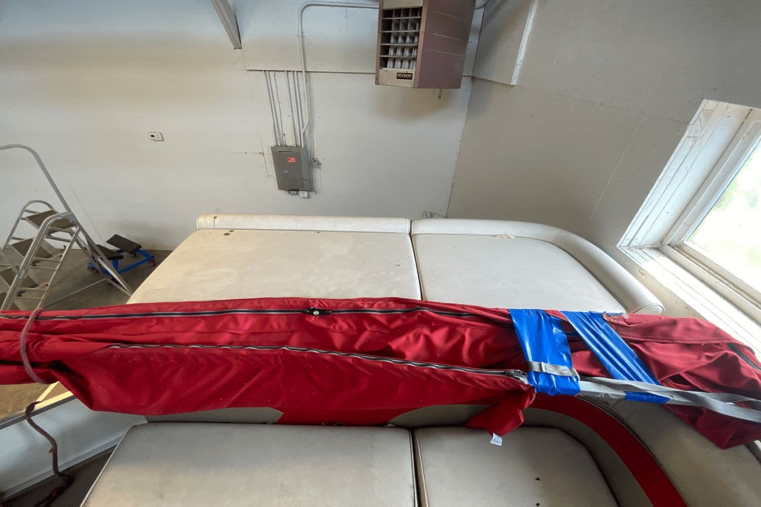 2007 Palm Beach 220 LX boat interior with red cover and blue tape in a garage.