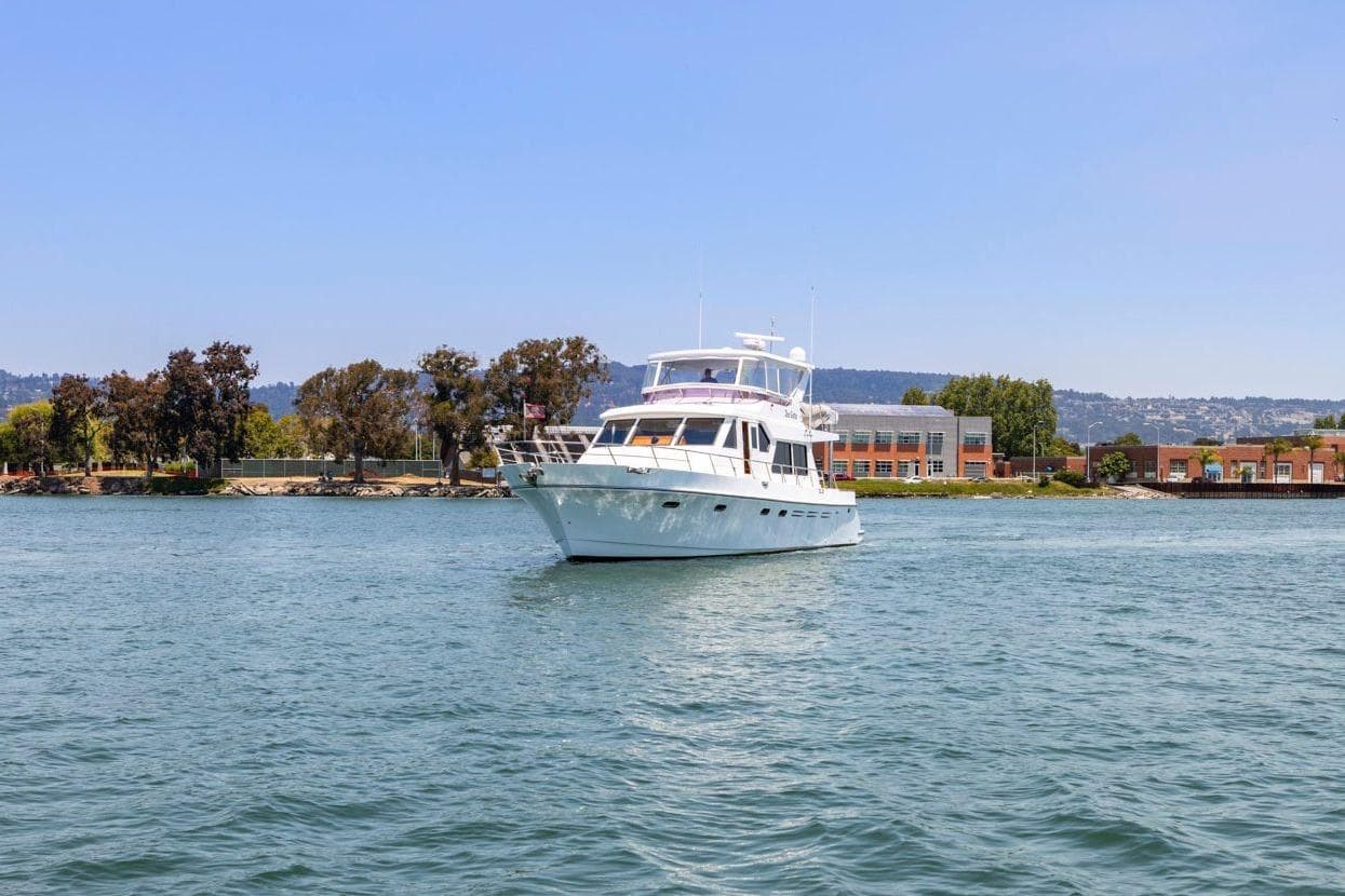 Luxury yacht Symbol 55, 1999 model, cruising on a serene waterway.
