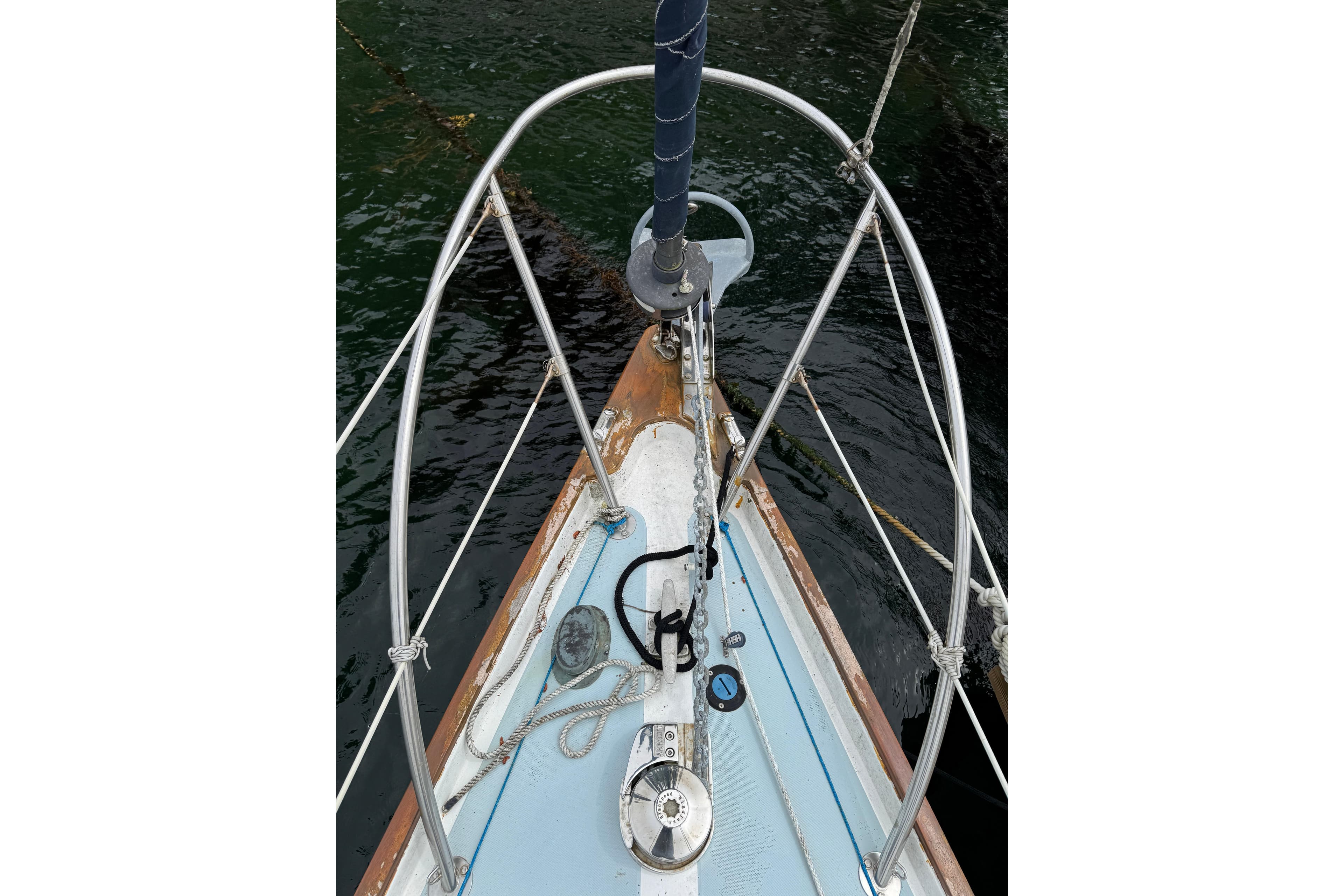 Bow of a 1972 Ranger sailboat with ropes and metal railings on water.