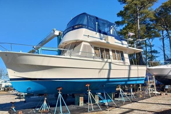2006 Mainship 40 Trawler on stands, blue and white, outdoors under clear sky.