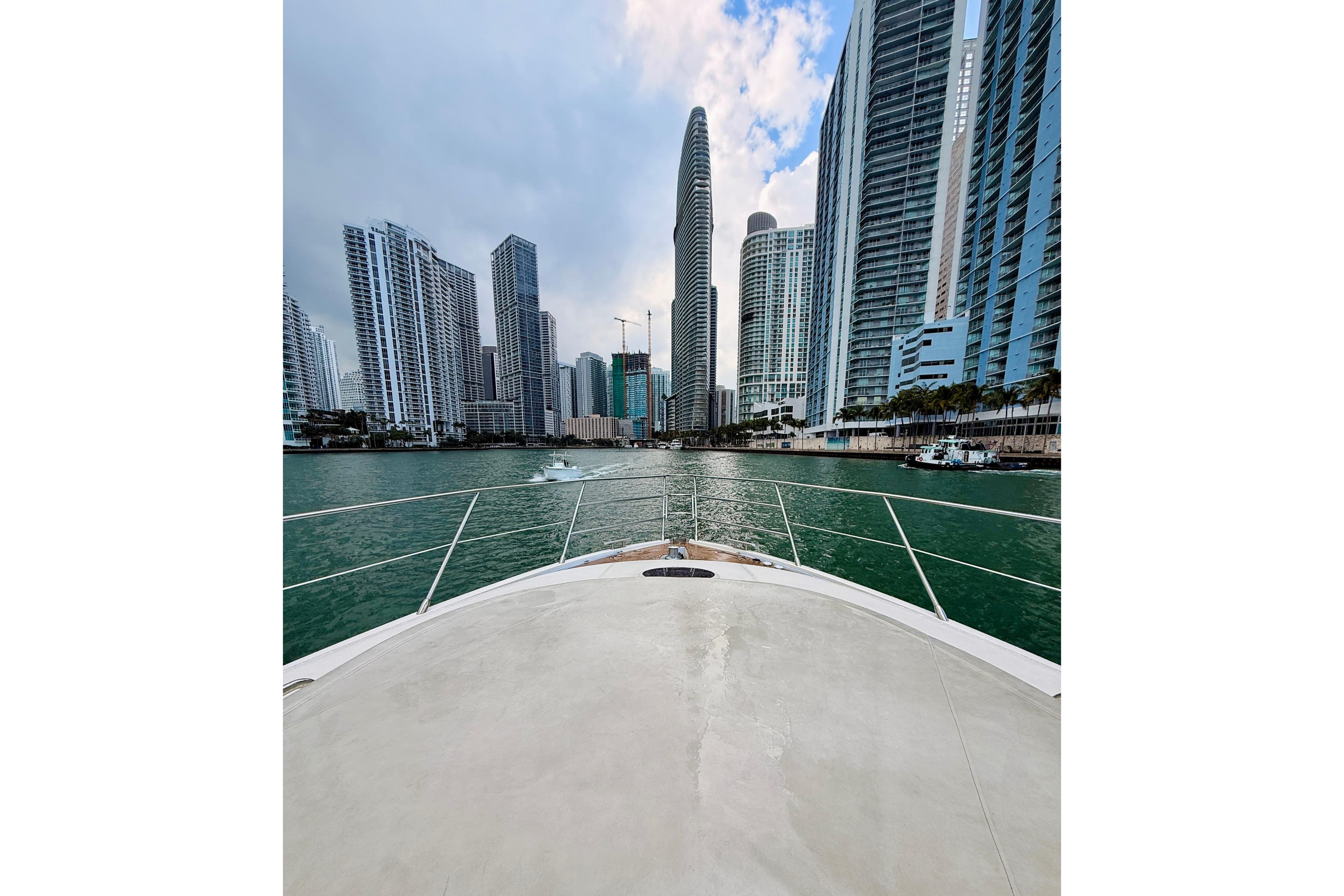 Bow view from 2007 Azimut 68E yacht, approaching city skyline with tall buildings.