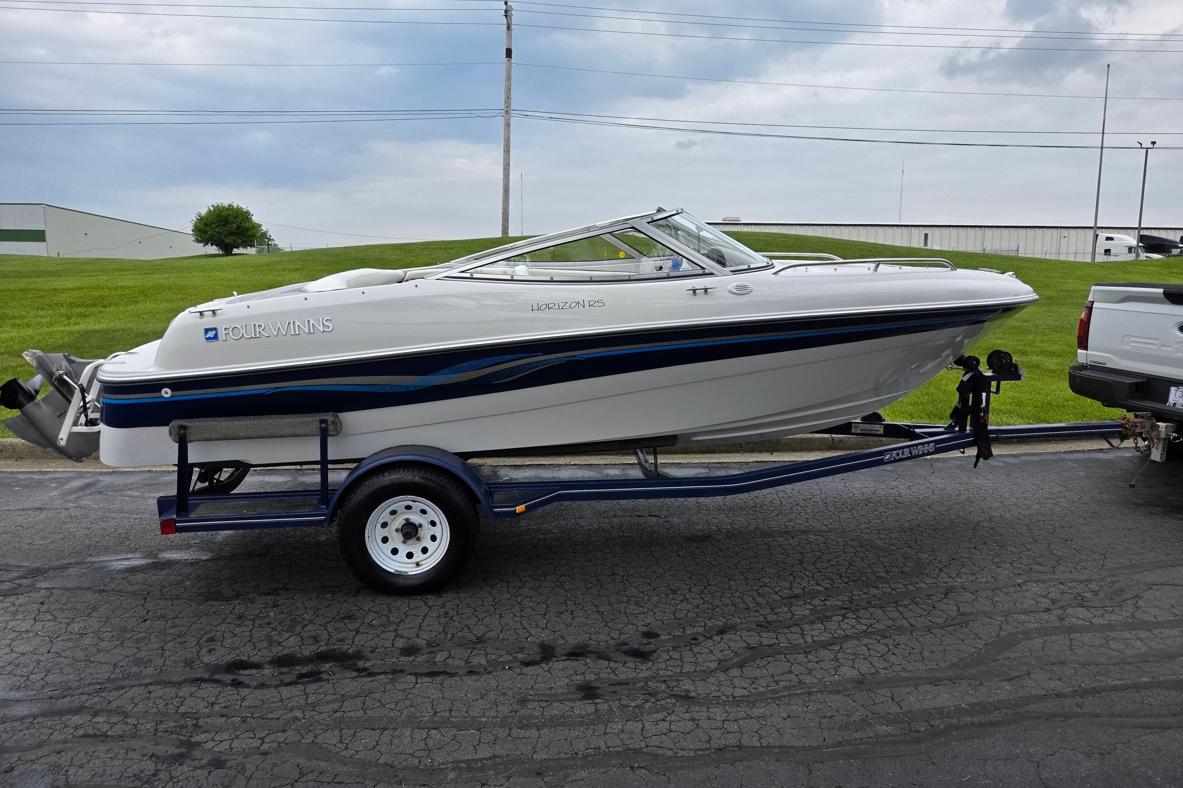 1998 Four Winns 180 Horizon boat on trailer, parked outdoors on a cloudy day.