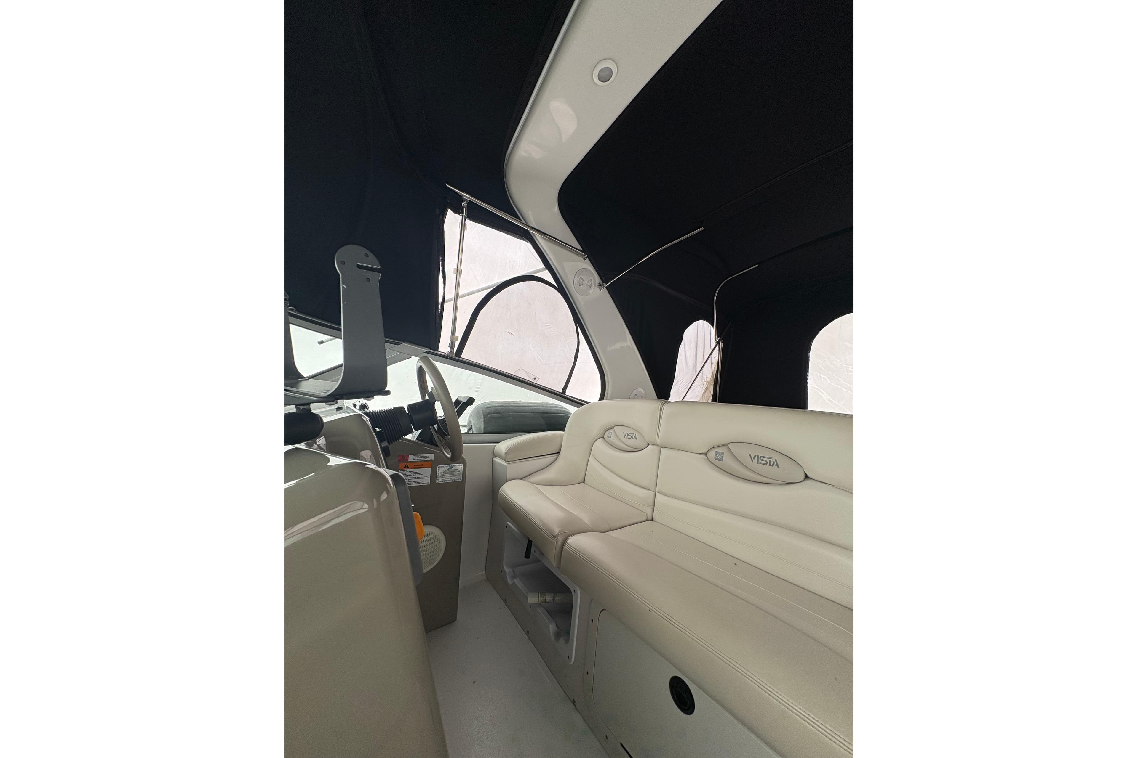 Interior of 1999 Four Winns 328 Vista boat with beige seating and steering area.