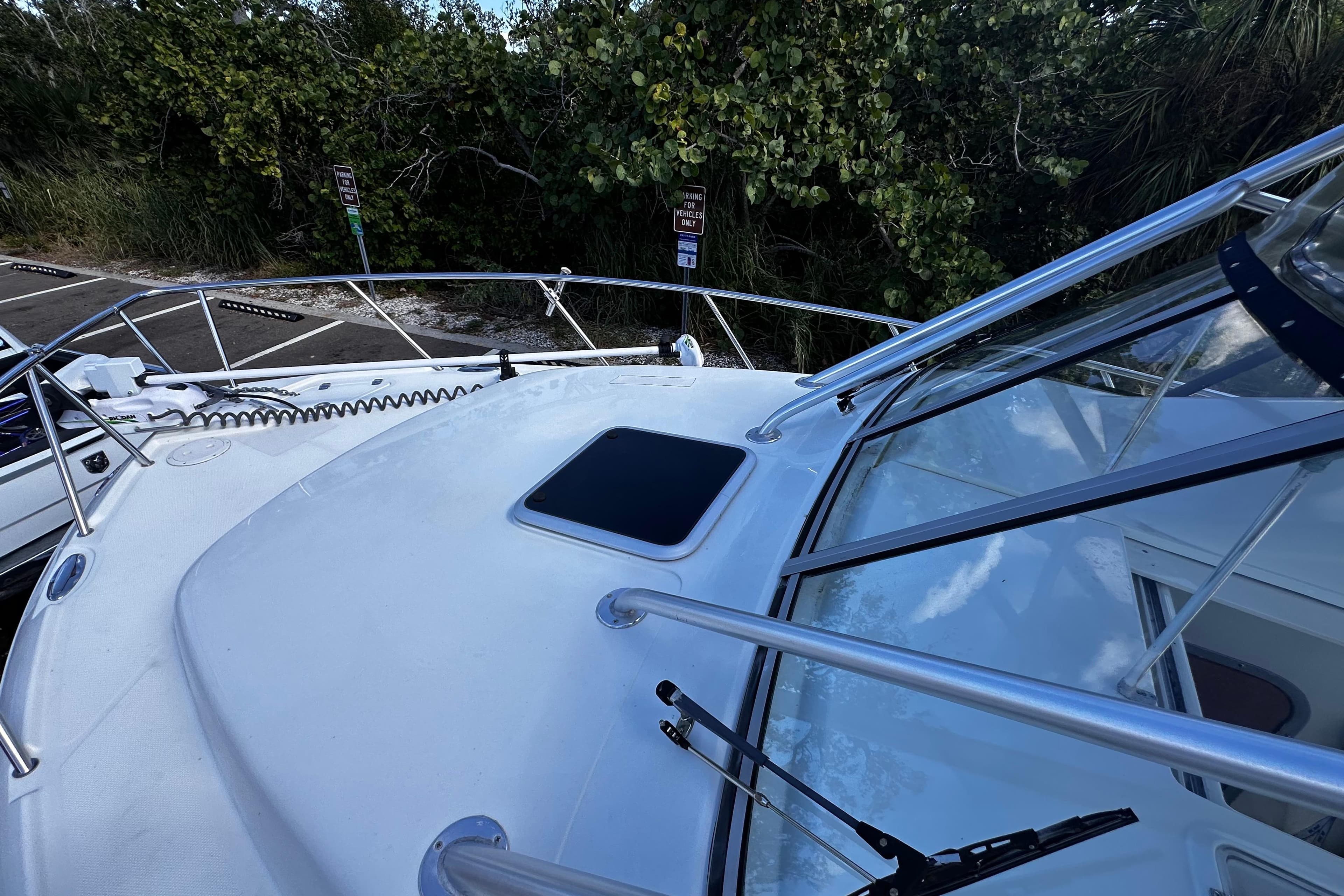 2008 Sailfish 3006 boat deck with railing and hatch, surrounded by greenery.