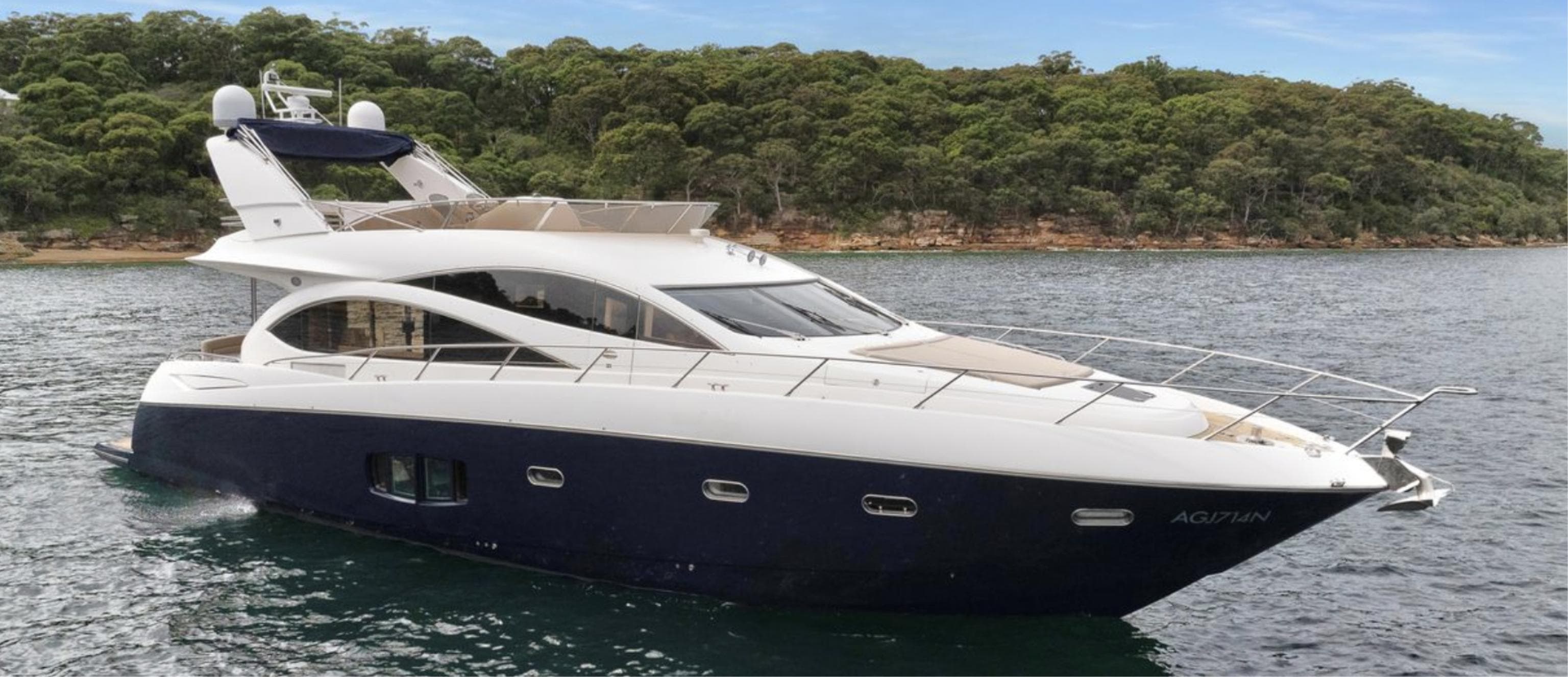 2009 Sunseeker Manhattan 70 yacht on water, with lush green shoreline in background.