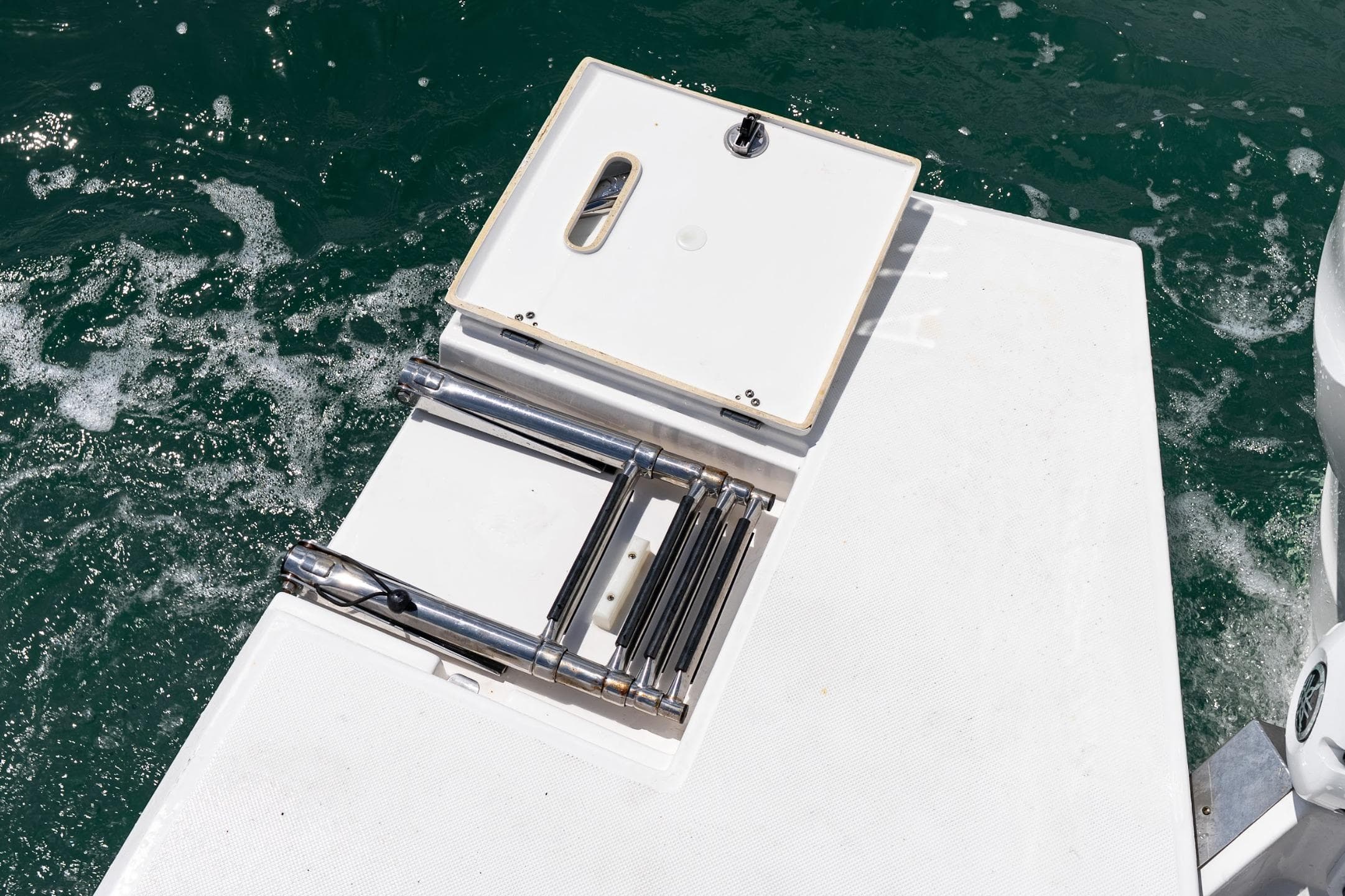 2023 Regal LX36 boat swim platform with ladder on water.
